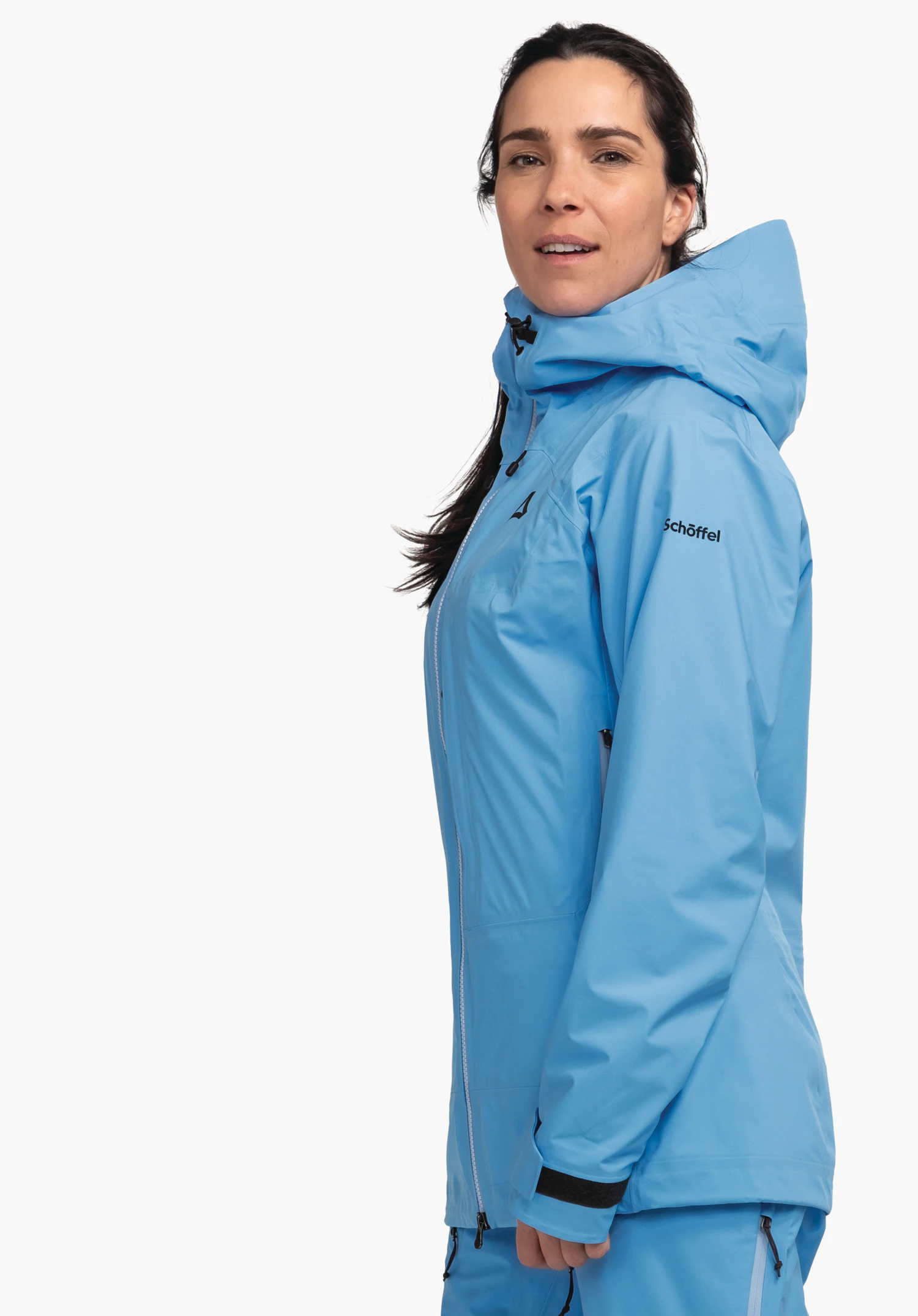Jacket Style Milagle WMS hellblaue Jacke mit Kapuze und schwarzem Schriftzug "Schöffel" sowie Schöffel-Logo; Person trägt sie seitlich, Kopf leicht gedreht, vor weißem Hintergrund.