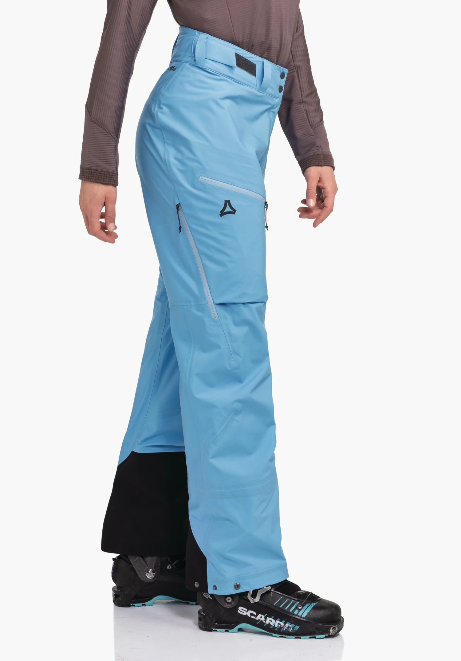 Pants Style Milagle WMS hellblaue Skihose mit Schöffel-Logo, seitlich getragen, steht auf weißem Hintergrund über schwarzen Skistiefeln mit Schrift "SCARPA".