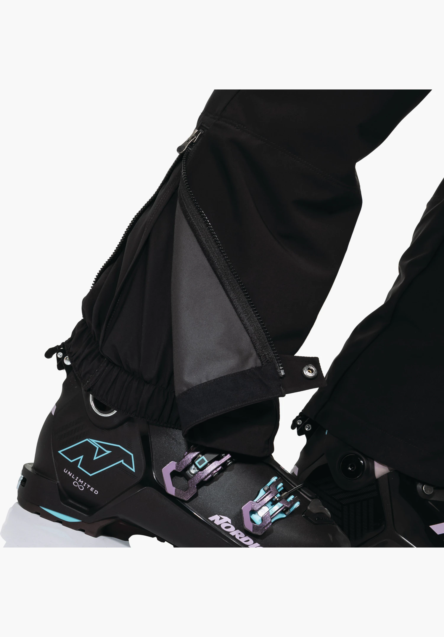 Softshell Pt Style Milagle WMS montrant le bas de jambe noir avec zip ouvert et soufflet d'aisance pour le réglage de la largeur ainsi que la guêtre pare-neige intégrée au-dessus de la chaussure de ski. Gros plan sur fond blanc/neutre.