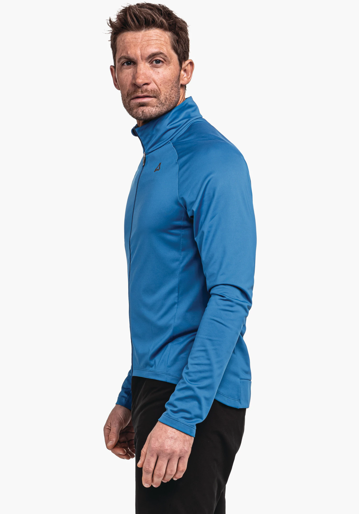 Longsleeve Style Kubena MNS adult man wears a light blue zip jacket, stands side-on and looks towards the camera; white background; Schöffel logo on chest.