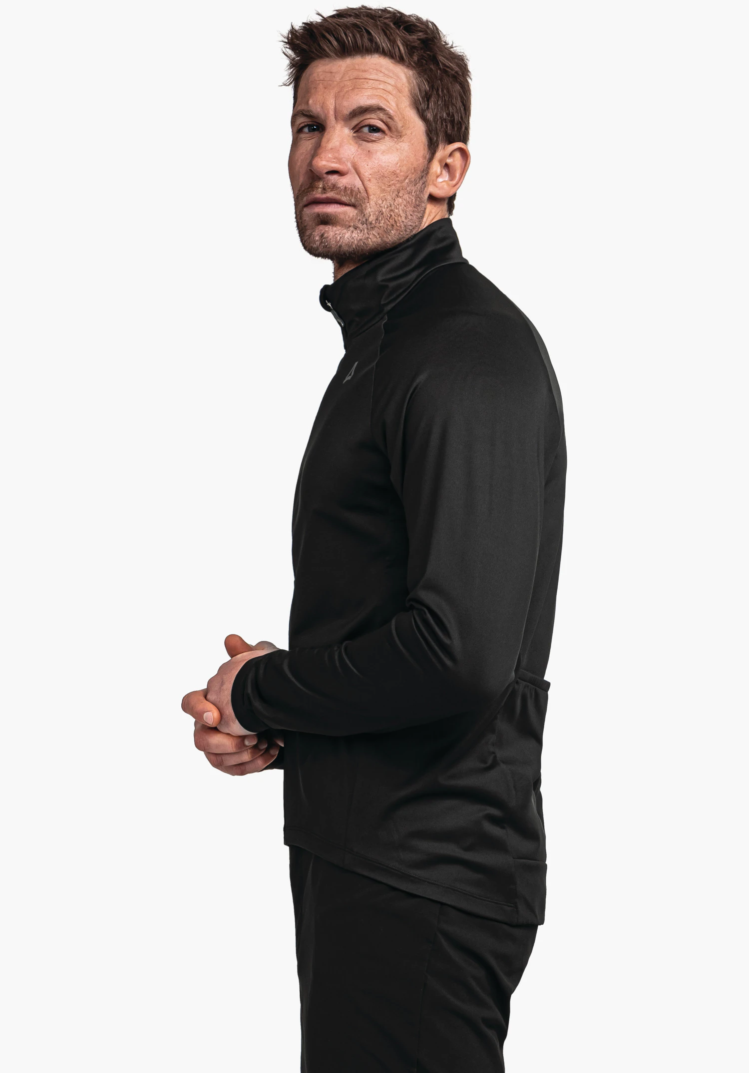 Longsleeve Style Kubena MNS black training jacket, man stands side-on with folded hands, Schöffel logo visible on chest, neutral white background.