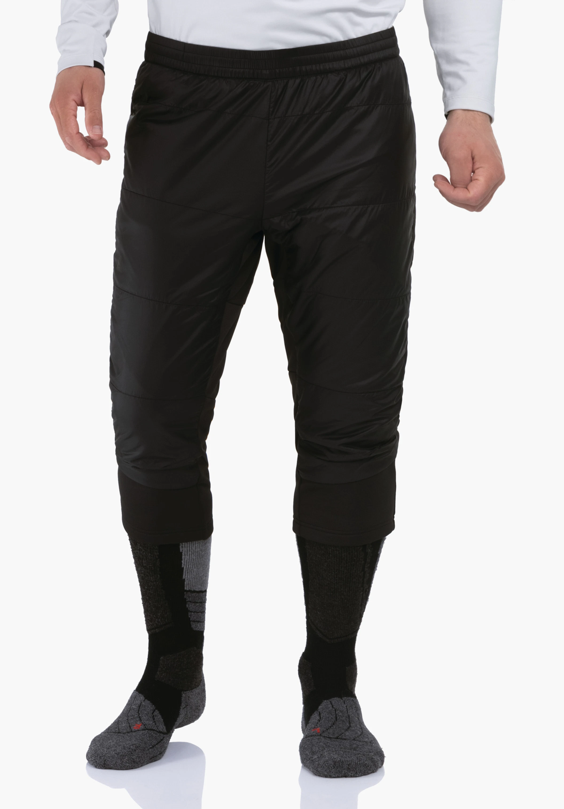 3/4 Pants Style Lufillo MNS pantalon noir longueur 3/4, porté par une personne debout; associé à des chaussettes de randonnée hautes noires et gris clair; haut blanc; fond clair neutre.