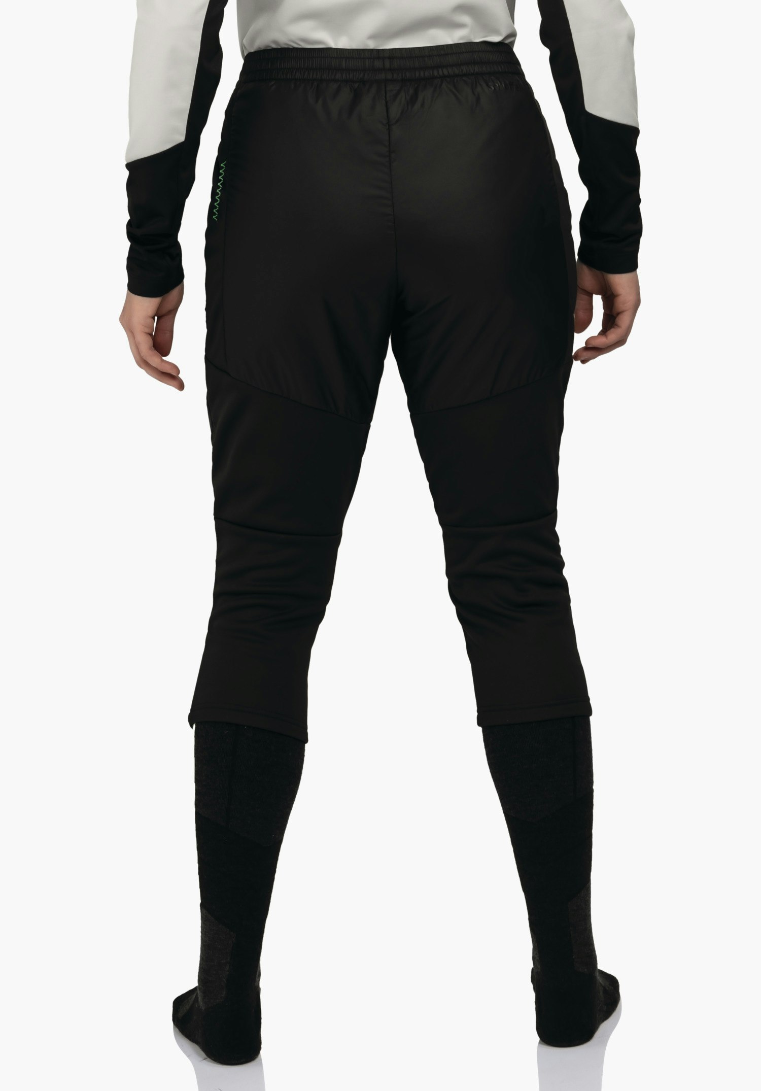 3/4 Pants Style Lufillo WMS zwarte trekkingbroek, van achteren gedragen; persoon staat met ontspannen hangende handen, lichtwitte mouwen met zwarte inzetten, donkergrijze en zwarte kniekousen, witte achtergrond.