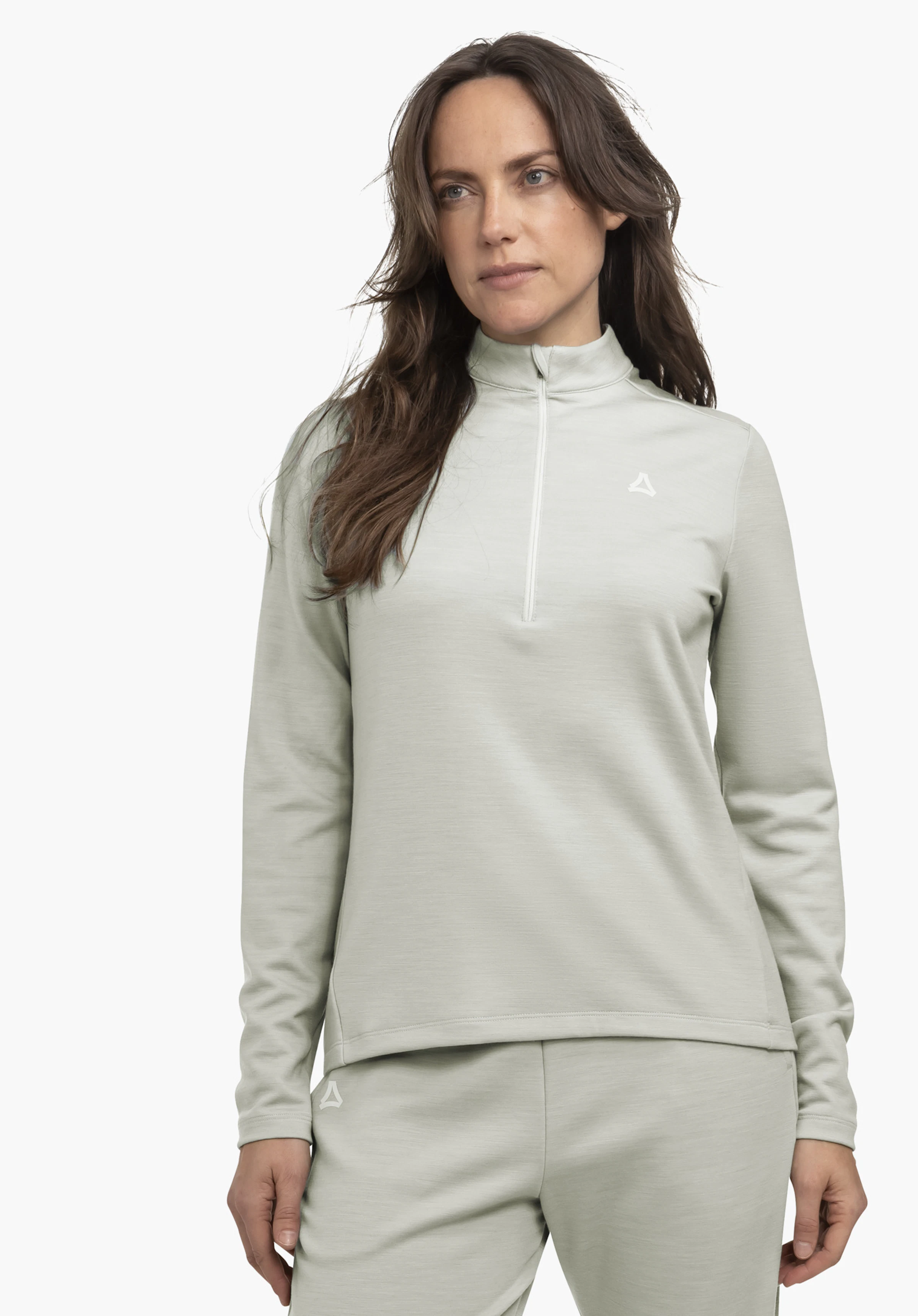 Longsleeve Style Canyfer WMS hellblaues Langarm-Top mit kurzem Reißverschluss; Frau trägt es und steht leicht seitlich; passende hellblaue Hose; neutraler heller Hintergrund; Schöffel-Logo sichtbar auf Brust und Hose.