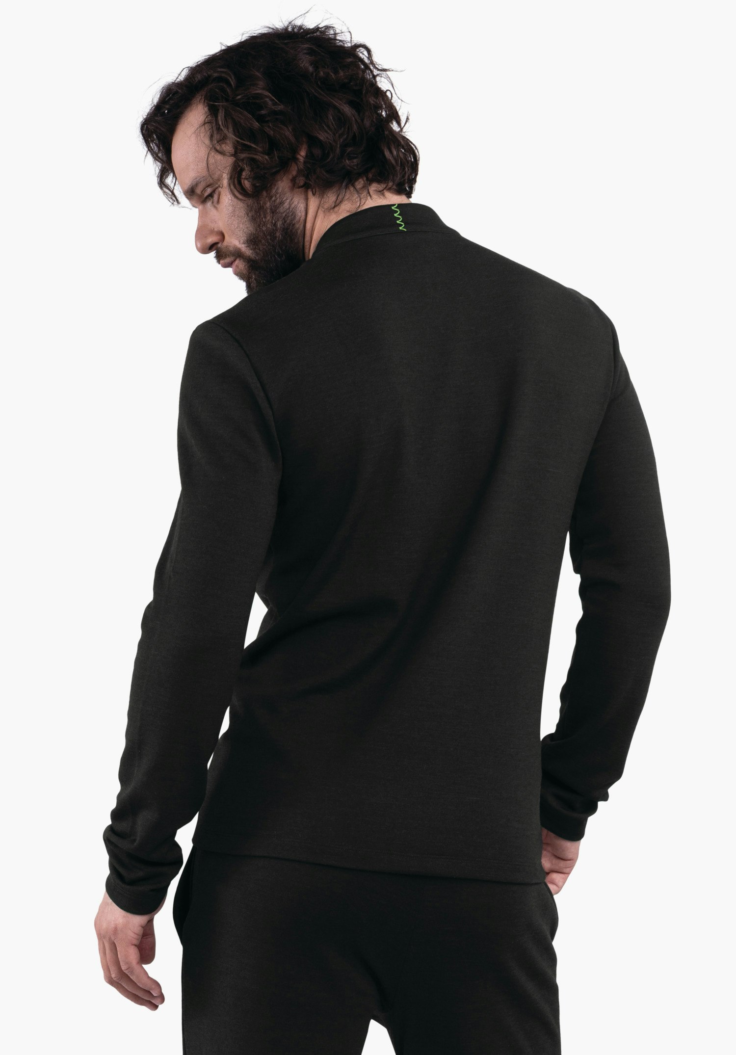 Longsleeve Style Canyfer MNS Mann trägt dunkelgrünen Langarmpullover, schaut über die linke Schulter; Hände locker an den Seiten; stehend vor weißem, einfarbigem Hintergrund.