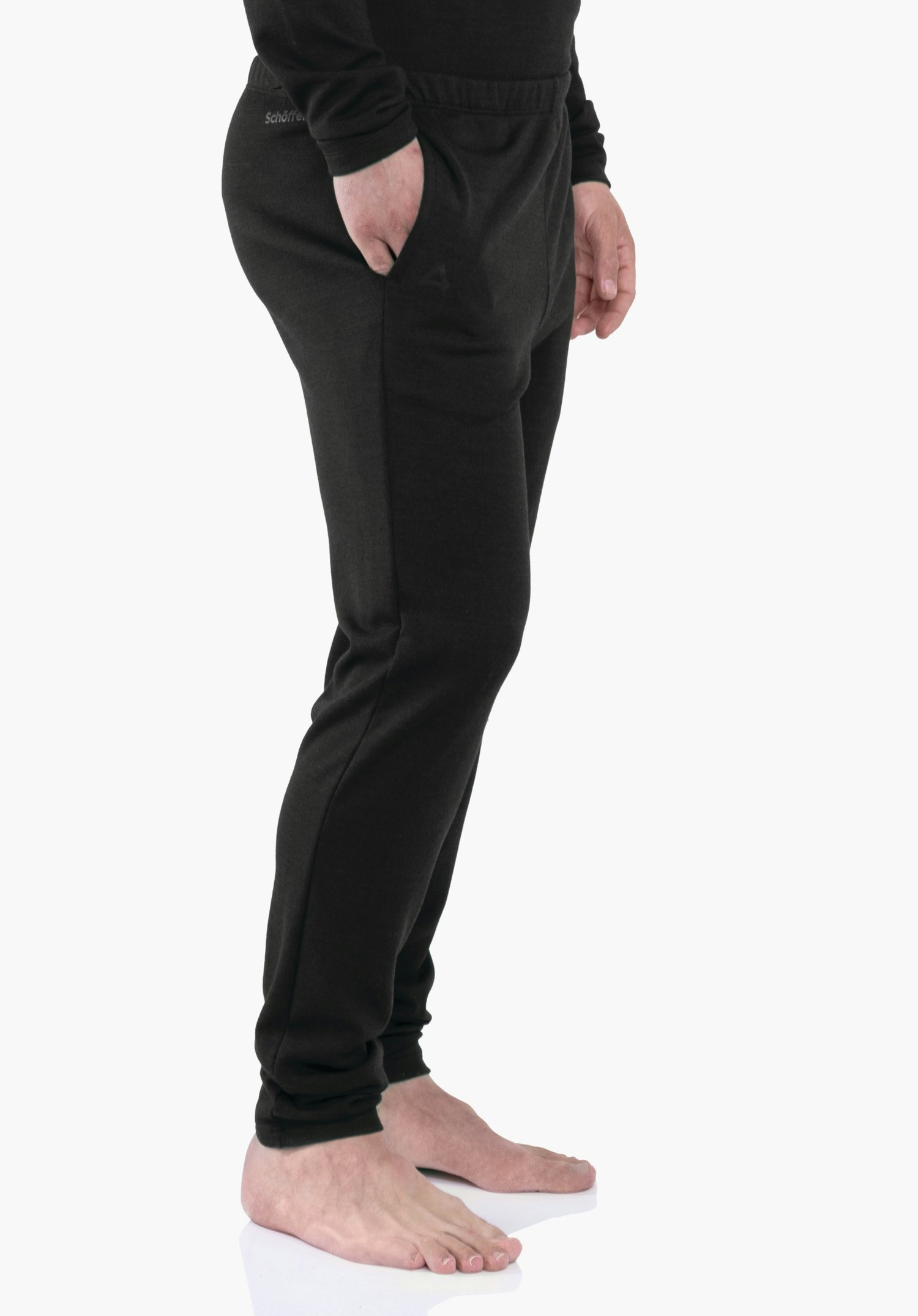 Pants Style Canyfer MNS Dunkelgraue Jogginghose, seitliche Ansicht; Person steht mit einer Hand in Tasche, barfuß auf weißem Studioboden. Schöffel-Logo sichtbar. Text: "Schöffel".