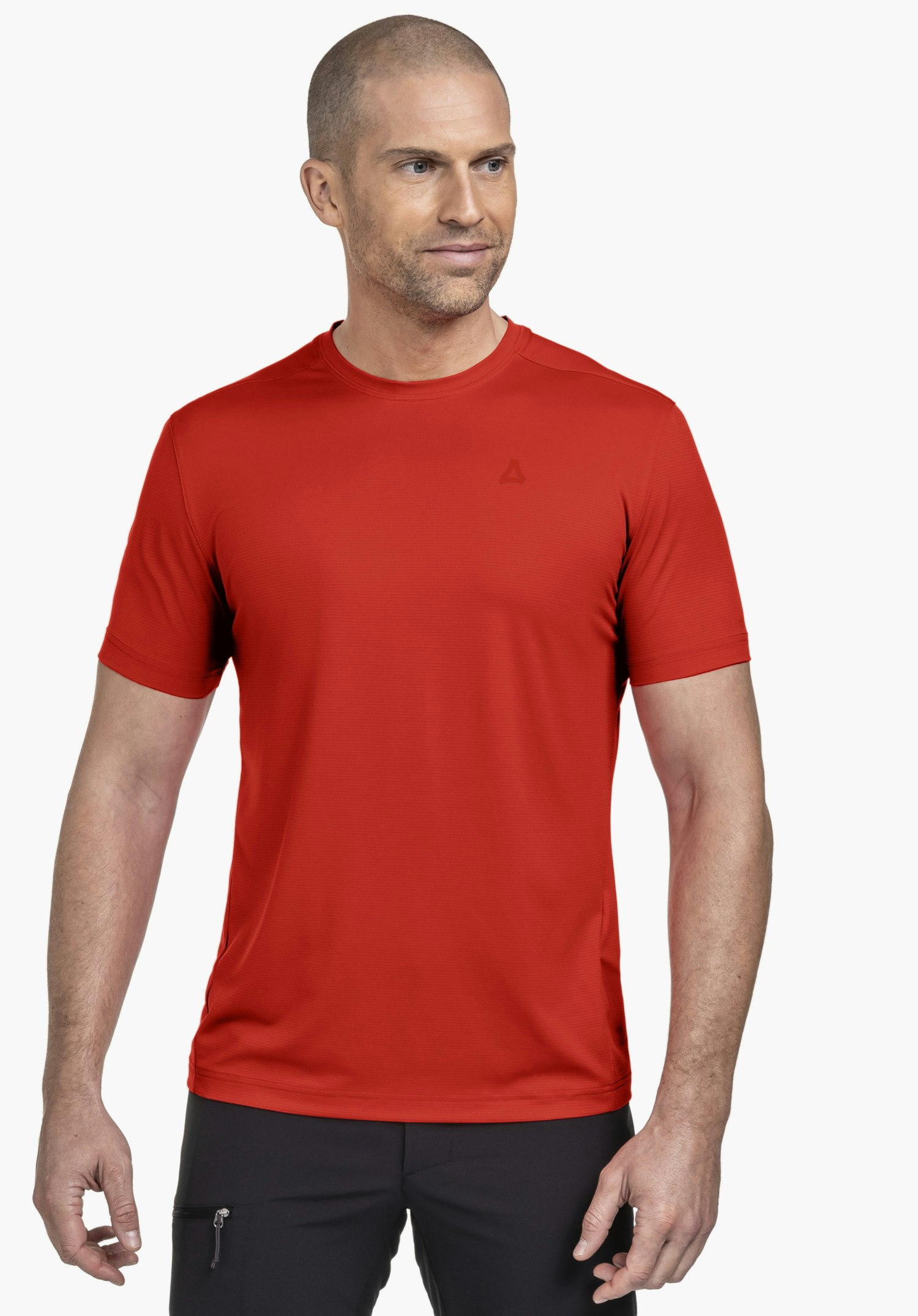 T Shirt Style Chipoma MEN präsentiert sich in einem leuchtenden Orange an einem Model, das frontal mit leichtem Blick zur Seite vor einem neutralen Hintergrund steht. Auf der Brust ist dezent das Schöffel-Logo platziert, was den sportiven Look abrundet.