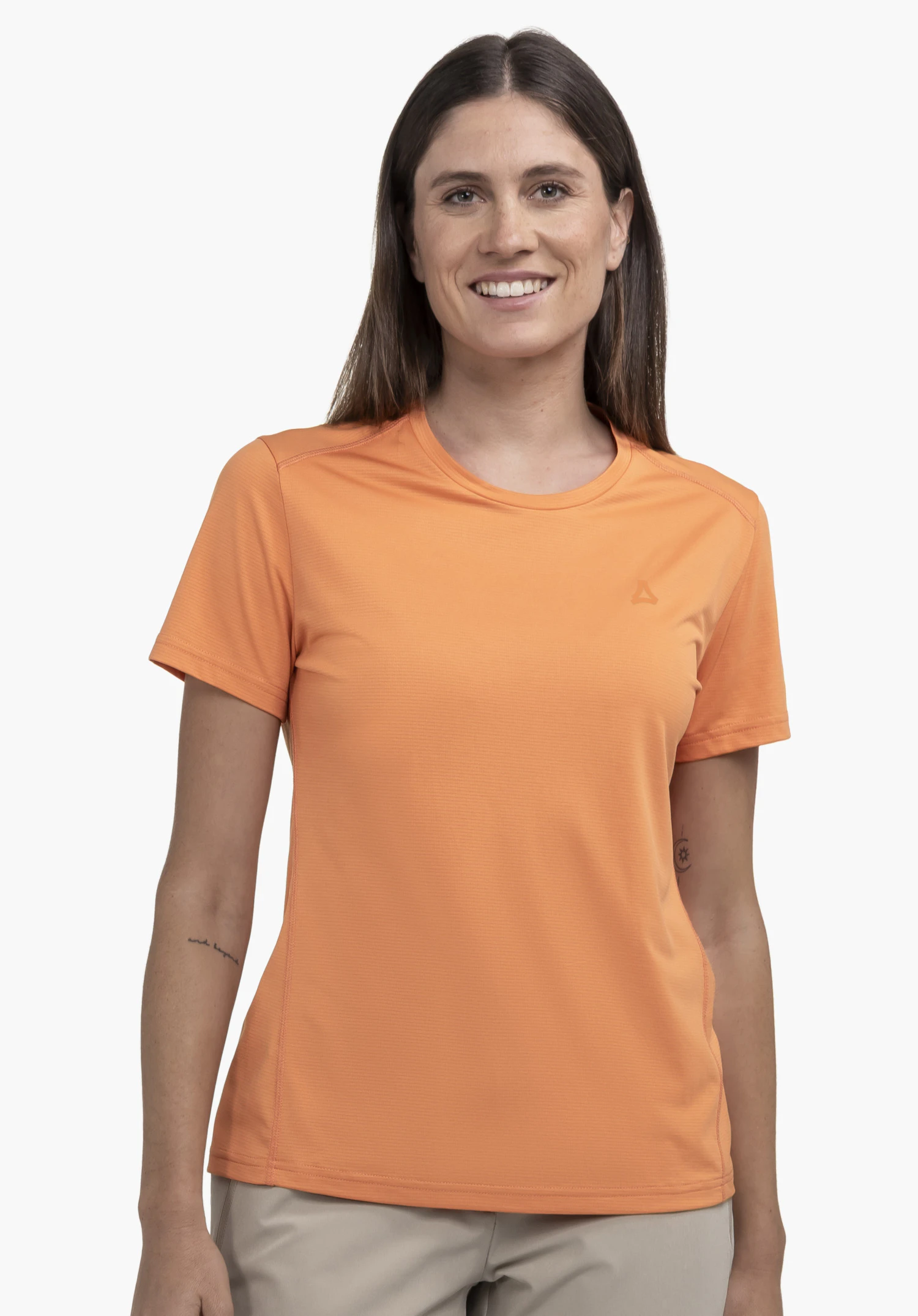 T Shirt Style Chipoma WMN, worn by a smiling model in a front-facing pose against a neutral background. This orange shirt features the subtle, tonal Schöffel logo on the chest, making it a perfect staple for your outdoor wardrobe.