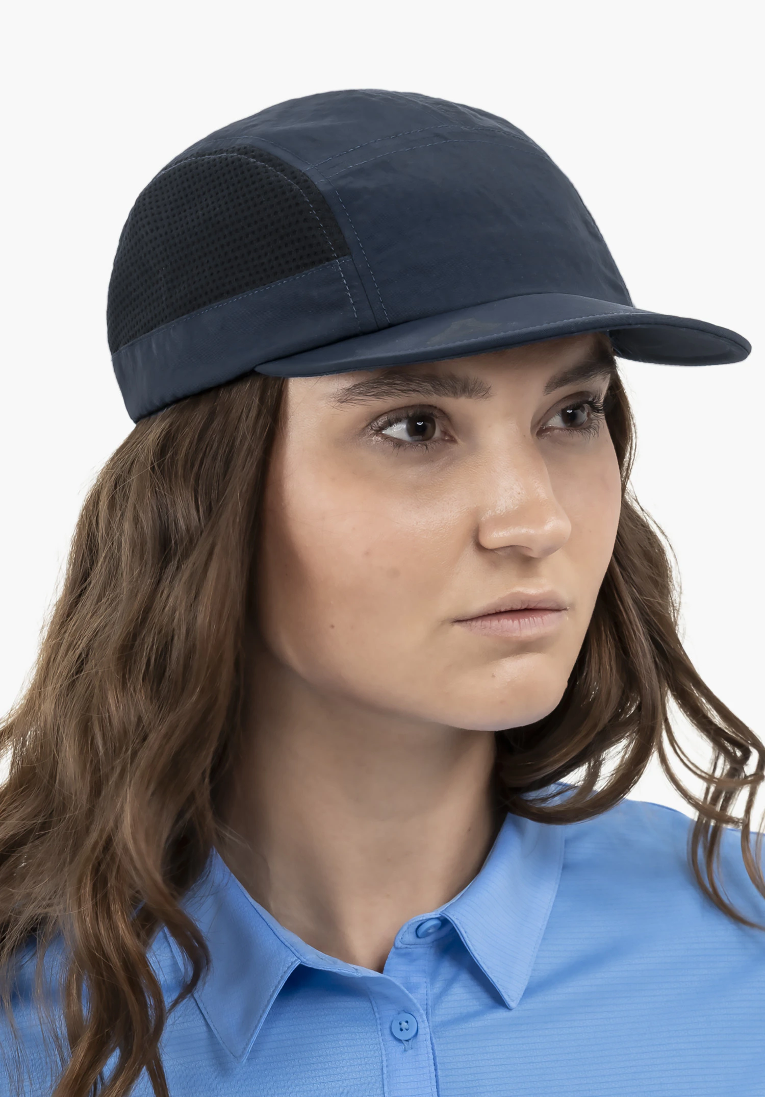 Cap Style Mauku UNI. A female model wears the blue cap in a close-up. The model is standing slightly sideways and looking to the side against a neutral background.