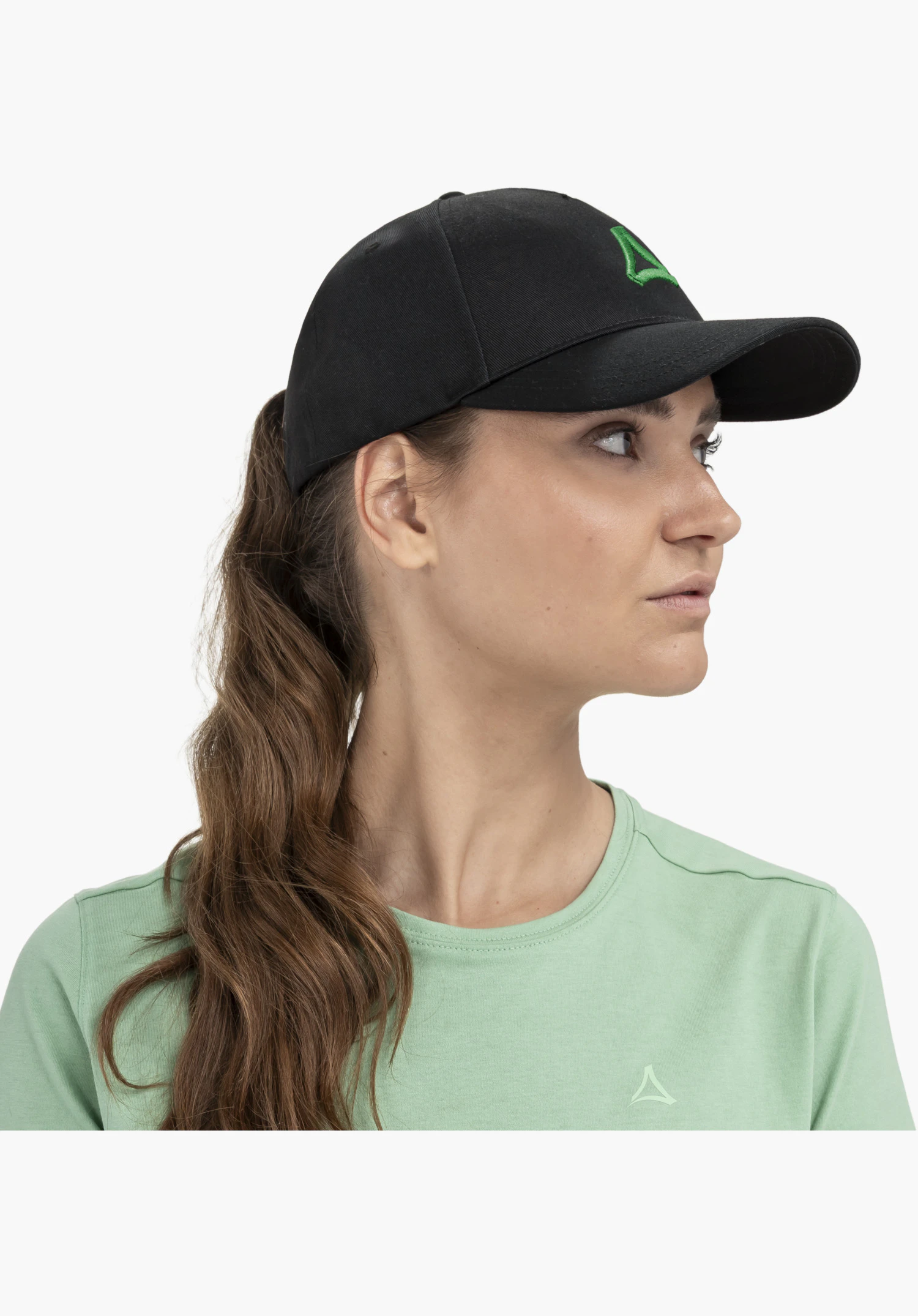 Cap Style Collada UNI features the prominent Schöffel logo embroidered in contrasting green on the black, high-quality cotton fabric. Close-up in front of a neutral background.