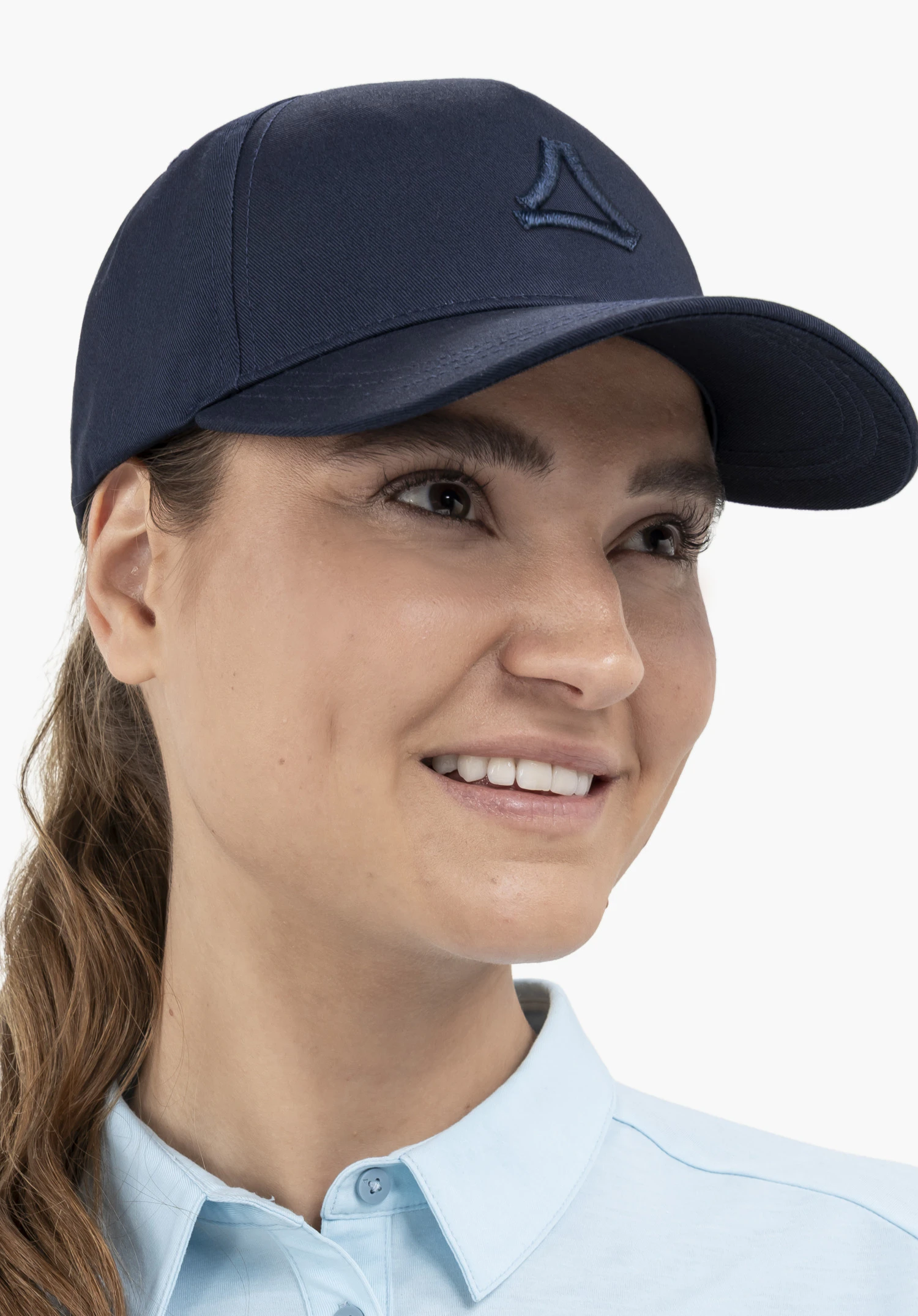 Cap Style Collada UNI in der Farbe Blau, getragen von einem Model in einer Nahaufnahme, das lächelnd zur Seite blickt. Das Schöffel-Logo ist auf der Vorderseite sichtbar, fotografiert vor einem neutralen Hintergrund.