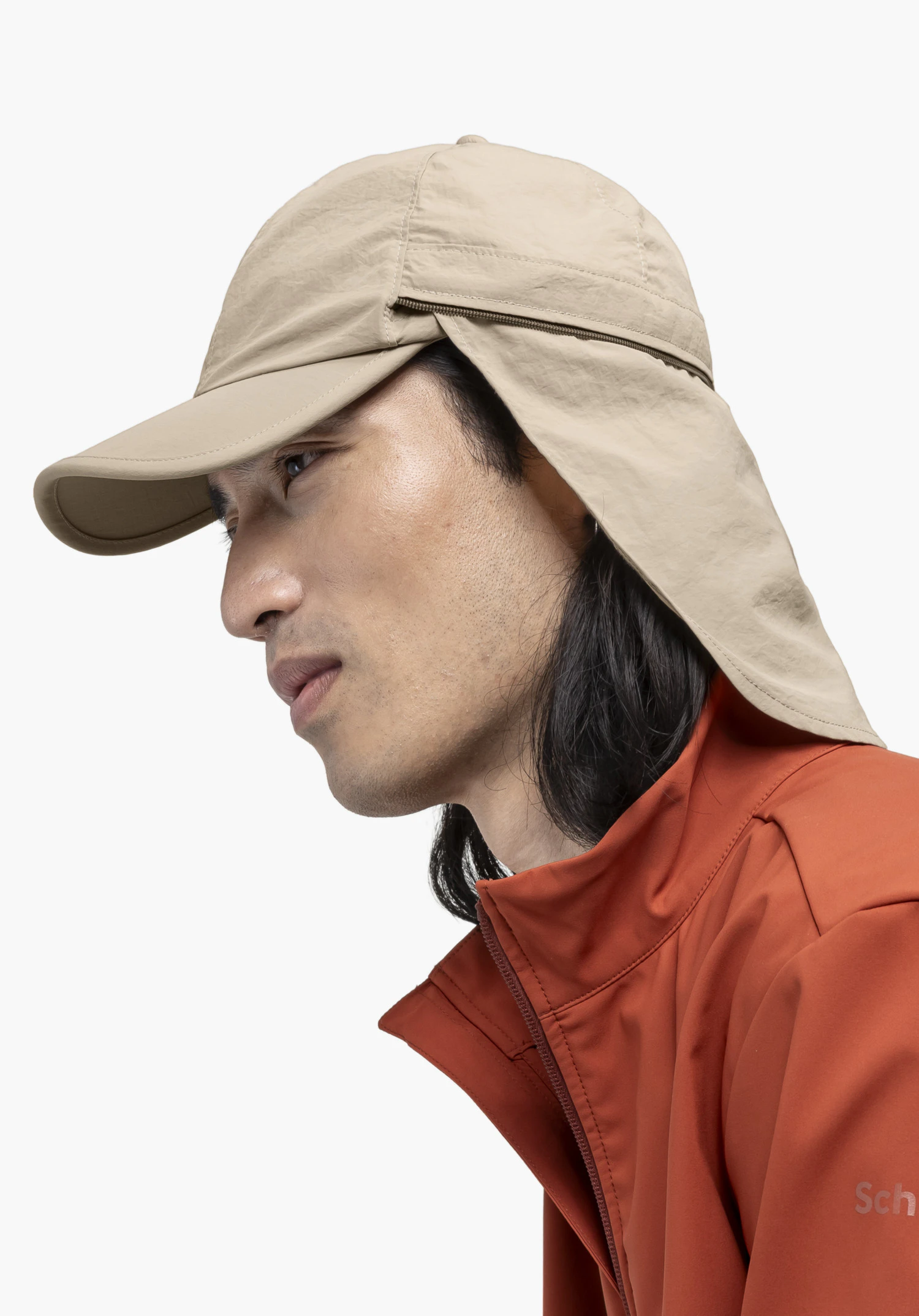 Cap Style Dalfoss UNI en beige, porté par un modèle photographié de profil. Devant un fond neutre, la vue met en avant la protection de nuque et le logo Schöffel discret sur la veste du modèle.