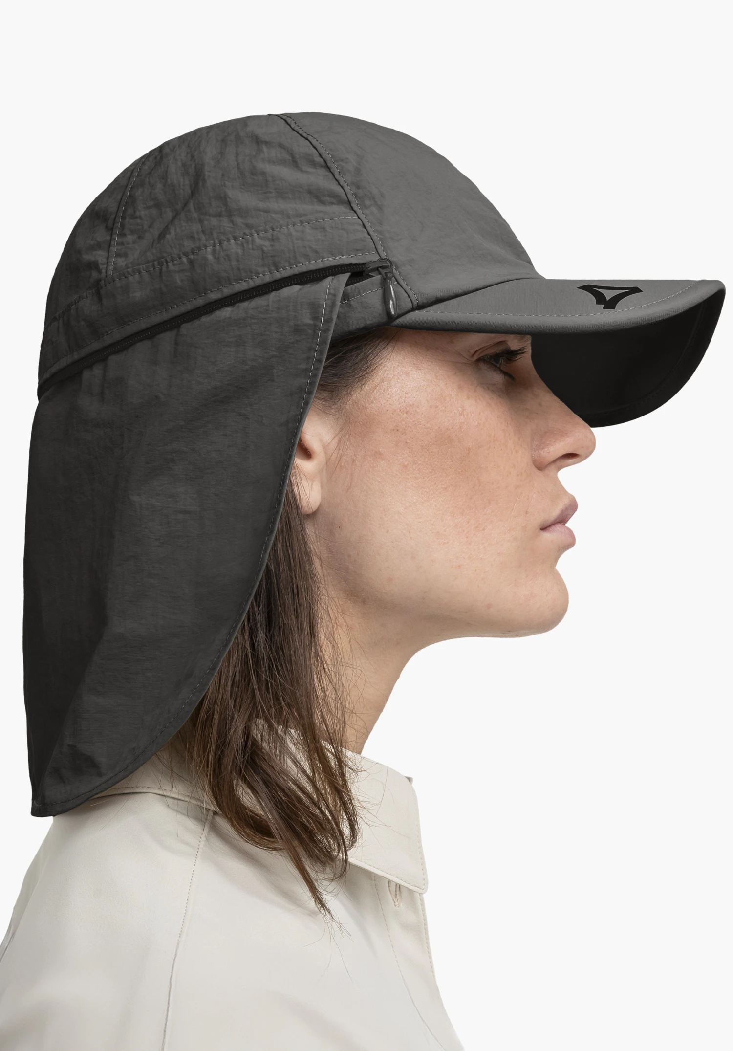 Cap Style Dalfoss UNI in grey. The model is standing in a side profile against a neutral background, showcasing the cap with its removable neck protection. The black Schöffel logo on the visor adds a distinctive detail.