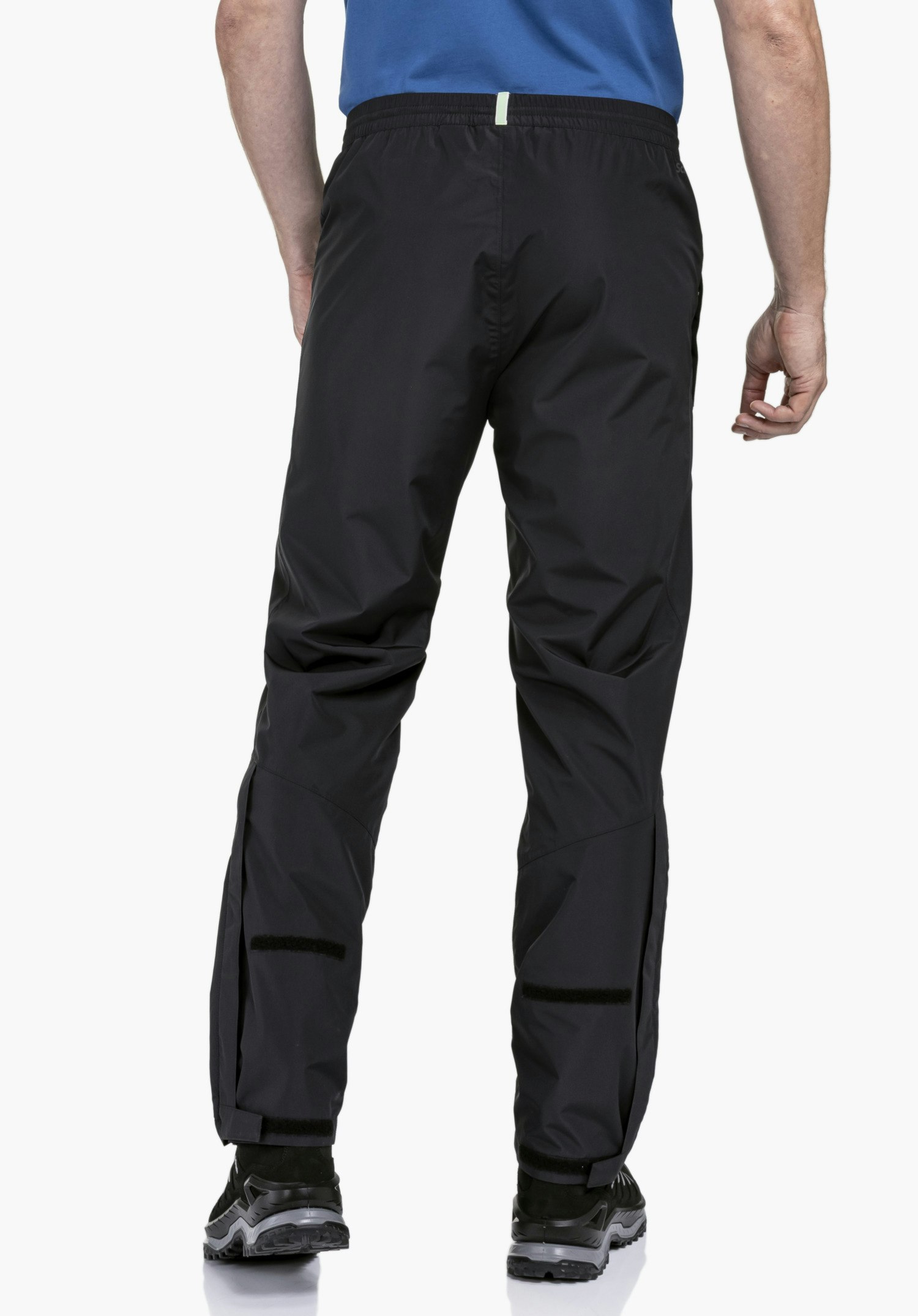 Rain Pants Style Elmori UNI in a rear view on a model in black with Schöffel logo against a neutral background.