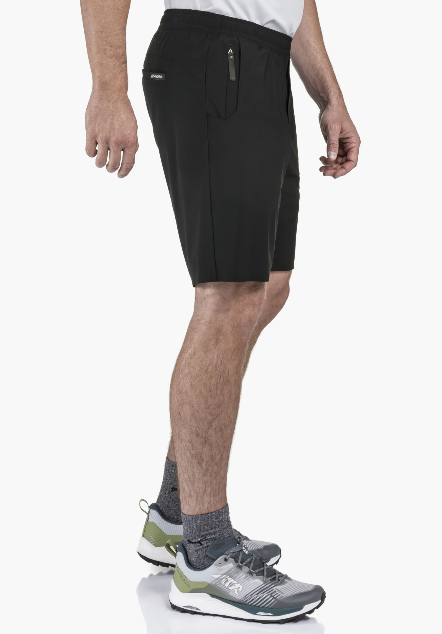 Jersey Shorts Style Calmay MEN en noir. Le mannequin est présenté de profil sur un fond neutre pour mettre en valeur la coupe du short. Le logo Schöffel discret sur la cuisse souligne le look sportif pour les journées actives.