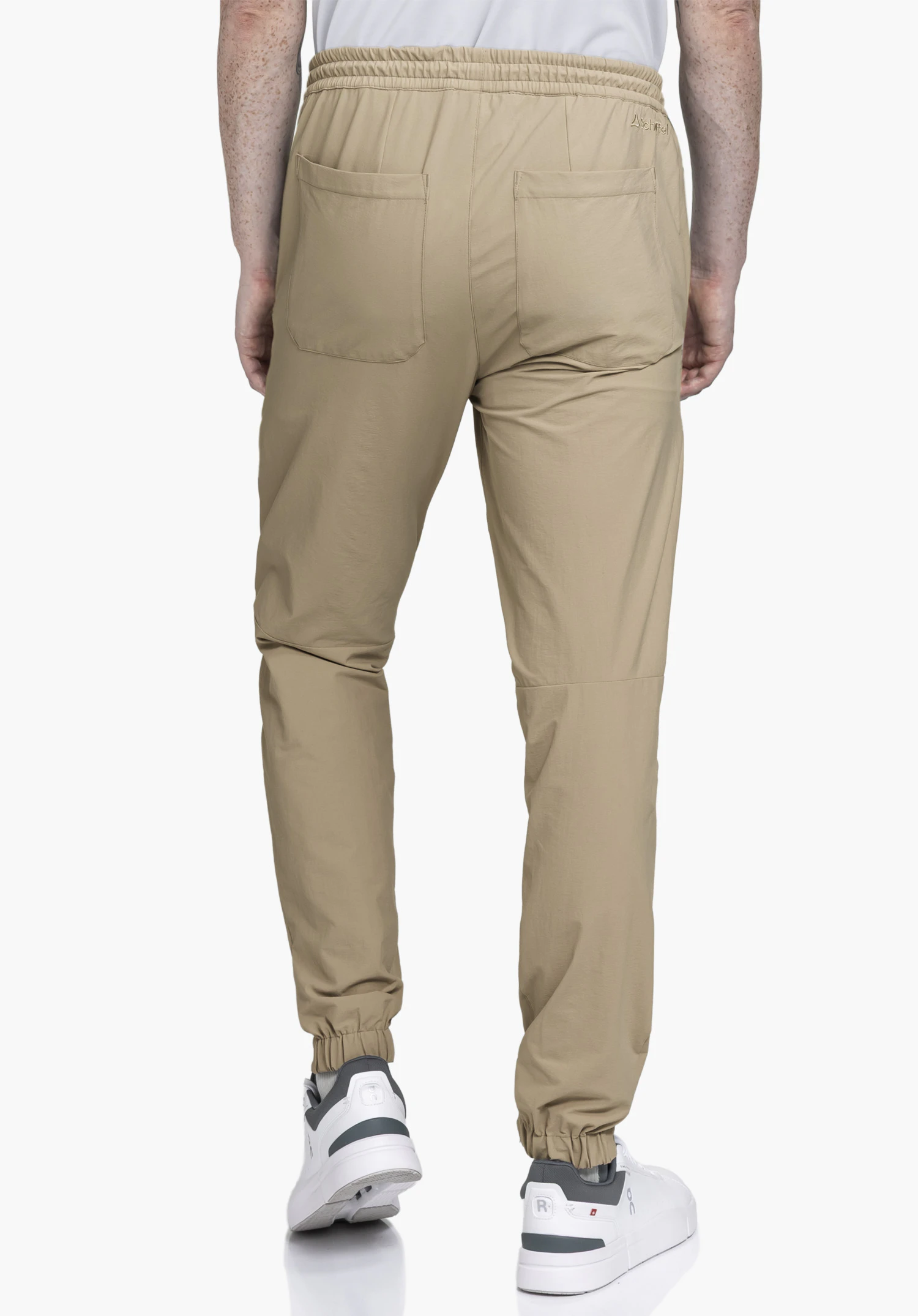 Pants Vienna M in beige on a model in a back view, showing the elasticated waistband, two back pockets and the Schöffel logo on the right side, photographed against a neutral background.
