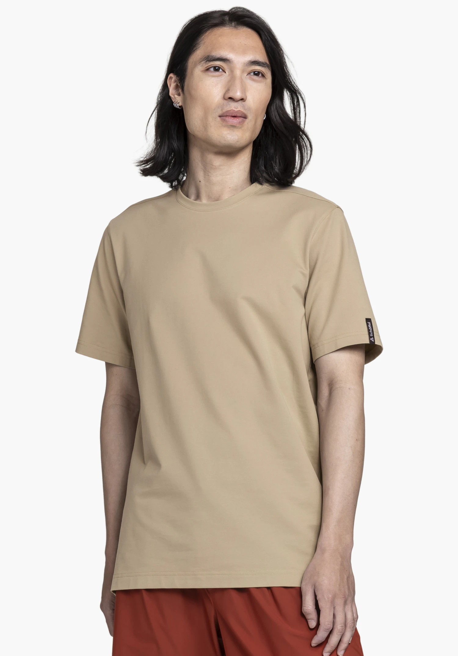 T Shirt Style Serenio MEN in beige, showcased by a model looking straight at the camera. The minimalist t-shirt stands out with its subtle color and a small, clearly visible Schöffel logo on the sleeve. The image is captured against a neutral background.