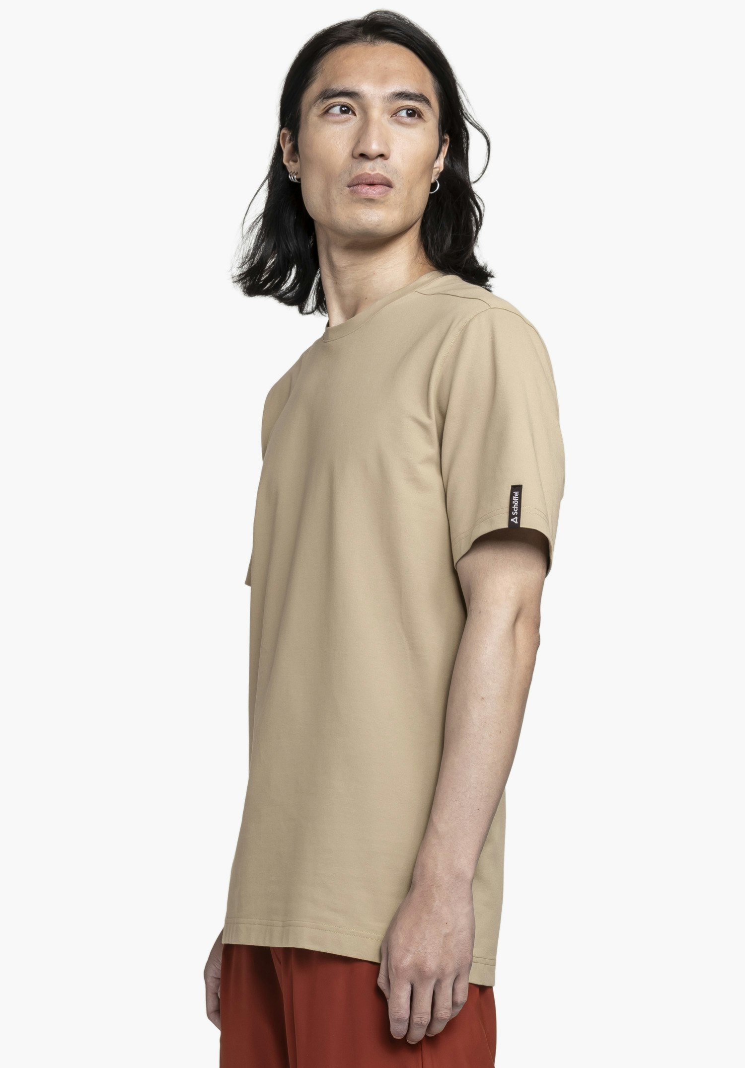 T Shirt Style Serenio MEN in Beige. Das Model steht seitlich vor einem neutralen Hintergrund und trägt das T-Shirt. Das dezente Schöffel-Logo am Ärmel ist gut erkennbar.