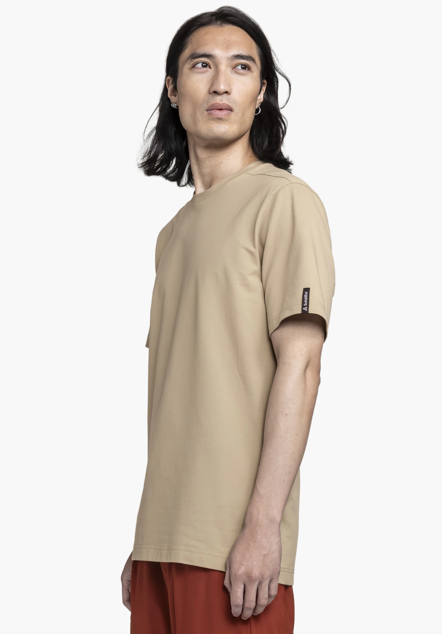 T Shirt Style Serenio MEN in beige. The model is standing sideways in front of a neutral background wearing the t-shirt. The subtle Schöffel logo on the sleeve is clearly visible.