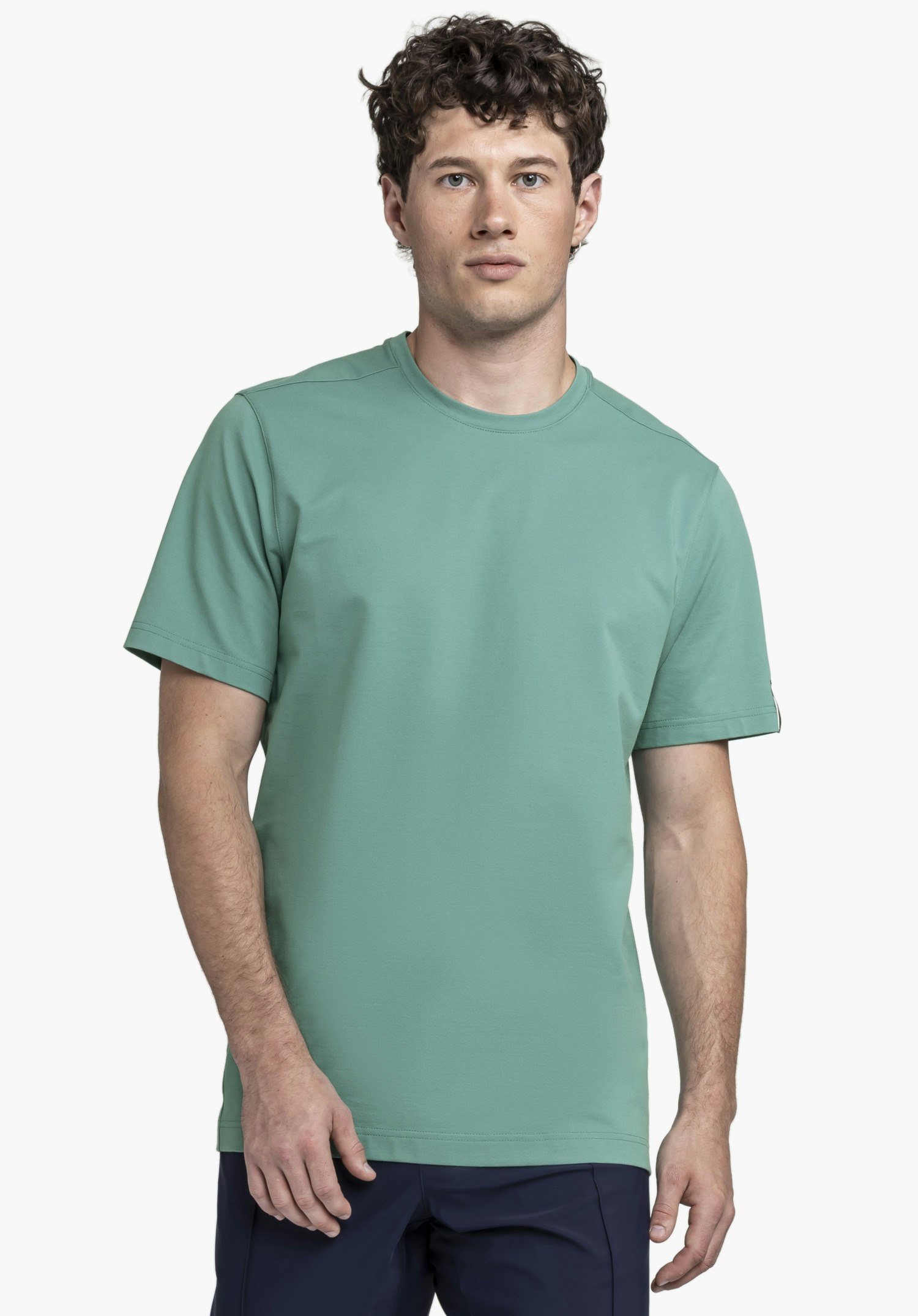 T Shirt Style Serenio MEN präsentiert sich in einem frischen Grün. Das Model steht frontal vor einem neutralen Hintergrund und trägt das Shirt mit einem dezenten Schöffel-Logo am Ärmel.