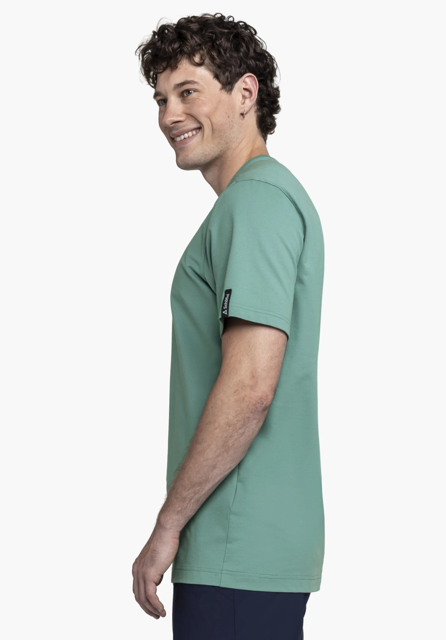 T Shirt Style Serenio MEN is presented in a fresh green shade. The model is standing sideways against a neutral background and smiling, while the Schöffel logo is subtly placed on the sleeve hem.