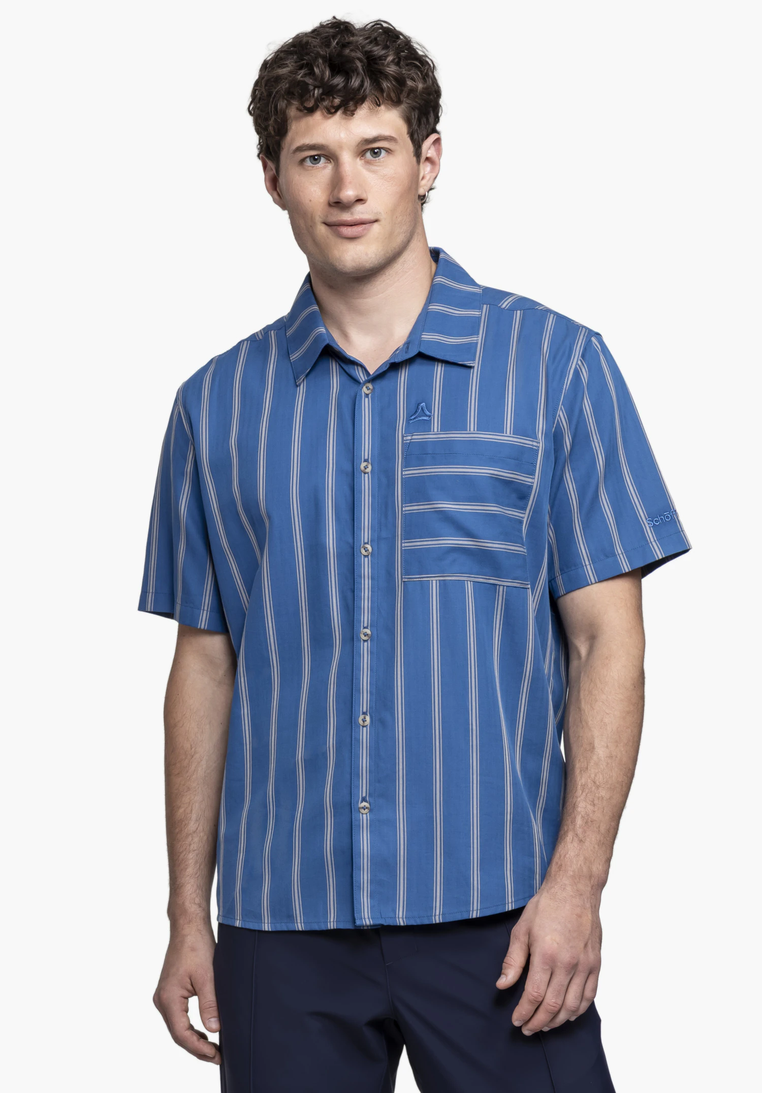 Shirt Style Kalmen MEN in blue. A model wears the short-sleeved shirt, facing the camera against a neutral background. The subtle Schöffel logo is visible on the chest pocket.