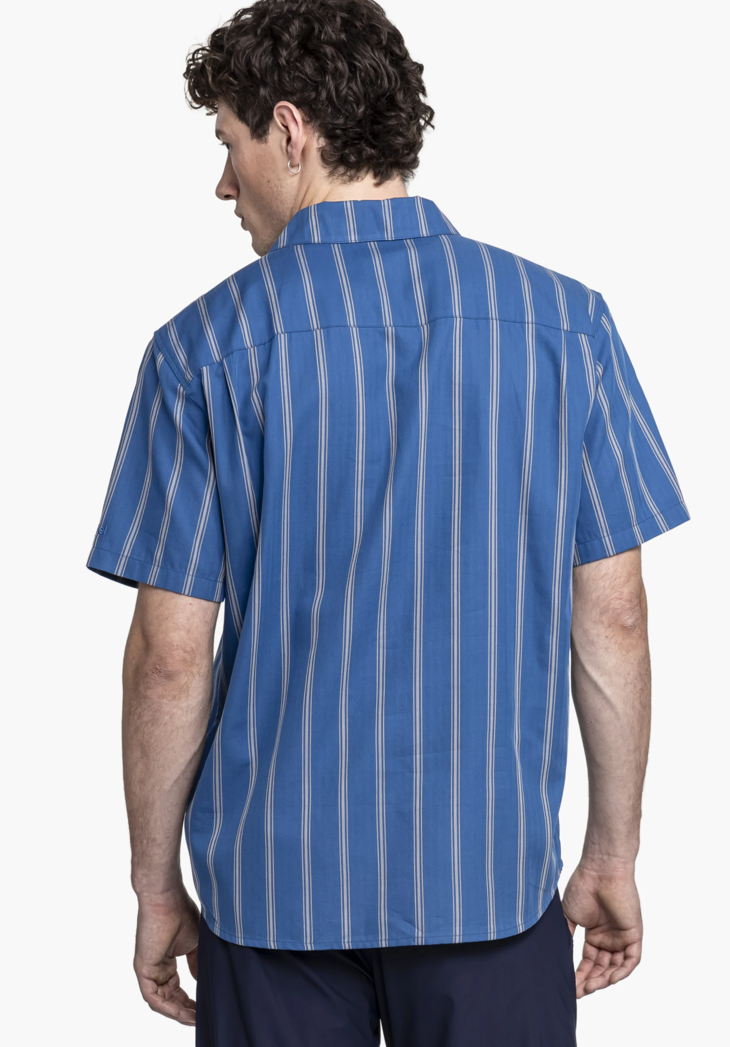 Shirt Style Kalmen MEN in Blau: Das Model steht in der Rückenansicht vor einem neutralen Hintergrund und präsentiert das gestreifte Hemd, wobei das dezente Schöffel-Logo am Ärmelsaum erkennbar ist.