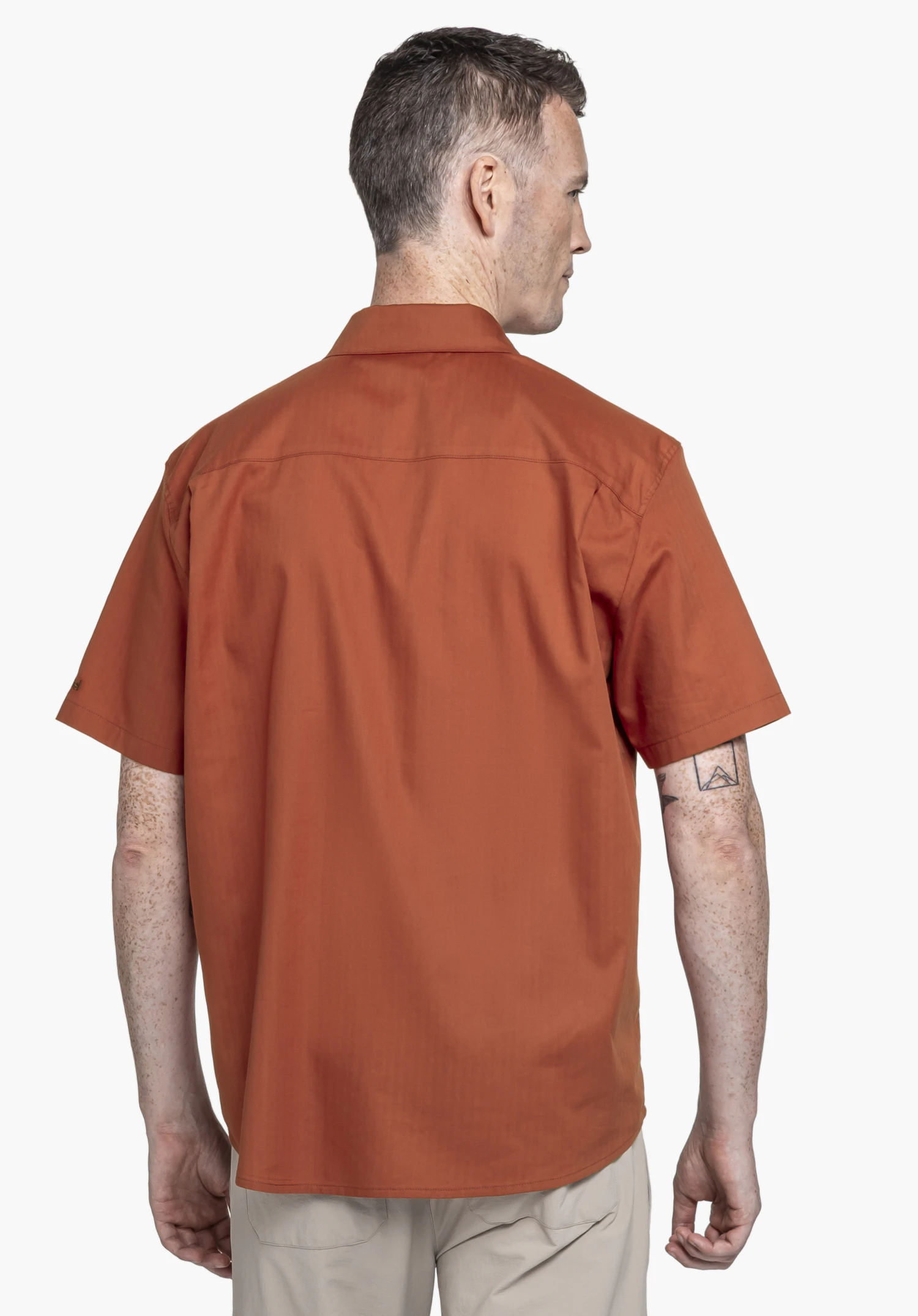 Shirt Style Kalmen MEN in Rot: Ein Model in Rückenansicht auf neutralem Hintergrund präsentiert das Hemd. Am Ärmelsaum ist dezent das Schöffel-Logo erkennbar.