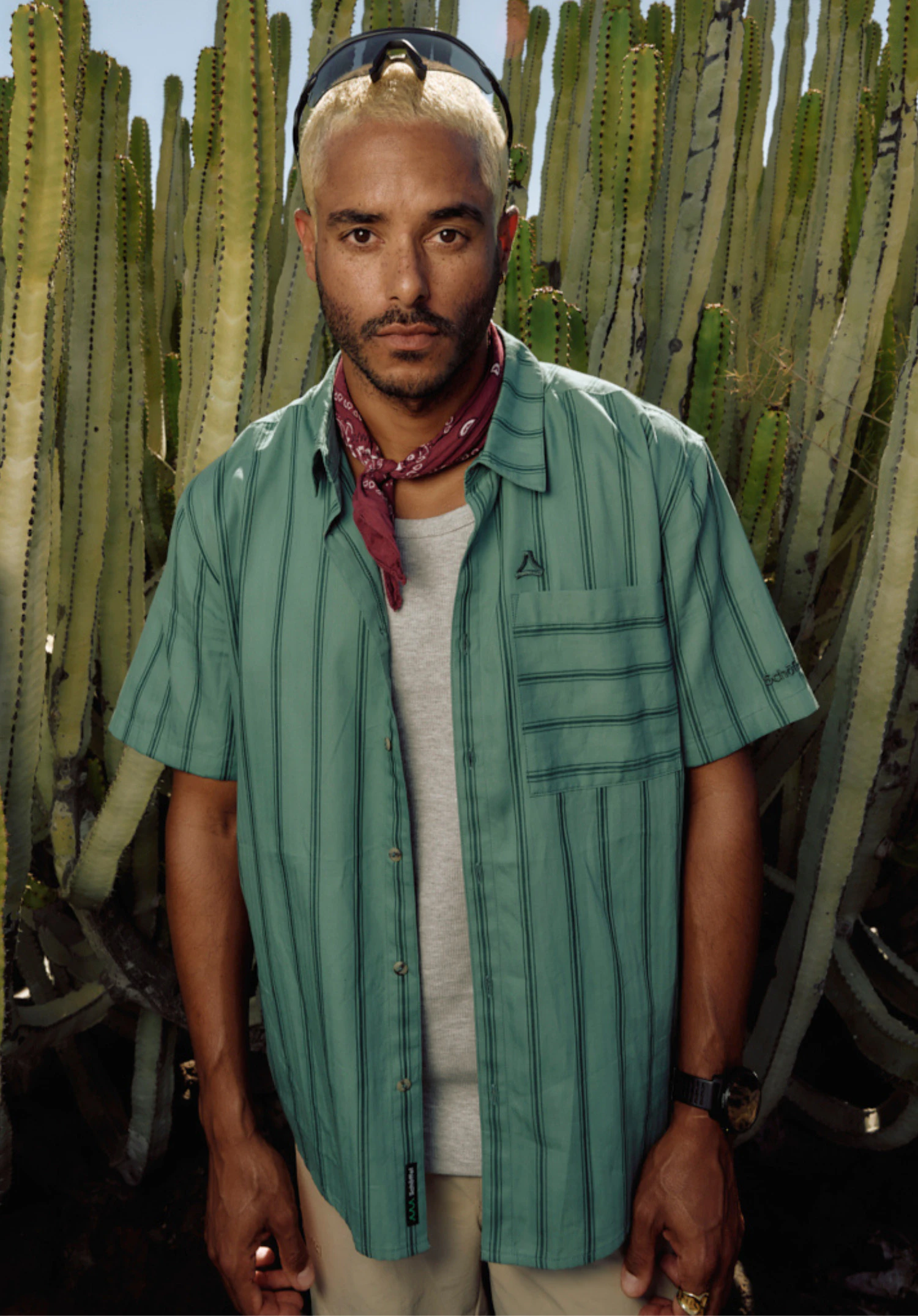 Shirt Style Kalmen MEN in green. A male model stands front-on against a neutral background wearing the short-sleeved shirt with a vertical stripe pattern. The small, subtle Schöffel logo is visible on the chest pocket and the lower hem.