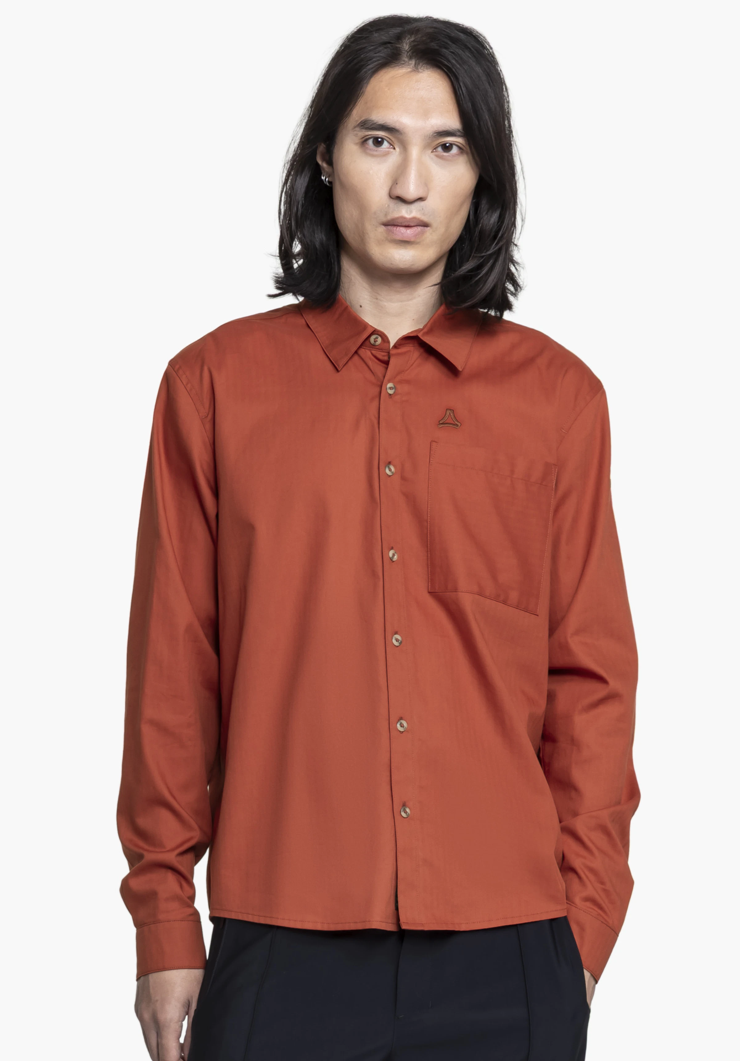 Shirt Style Chanduy MEN: Das Model steht frontal vor einem neutralen Hintergrund und präsentiert das Hemd in Rot. Das dezente Schöffel-Logo ist als Detail auf der Brusttasche erkennbar.