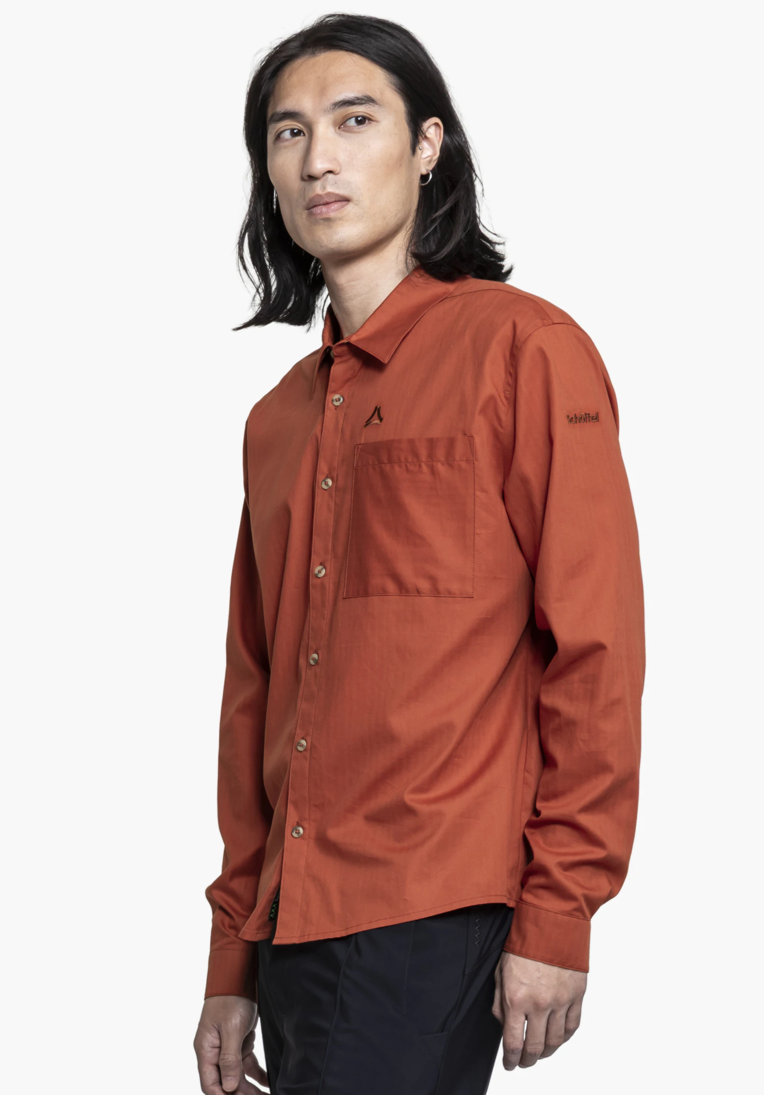 Shirt Style Chanduy MEN in red: A model is posing in a semi-profile view against a neutral background. The shirt features a relaxed fit, a chest pocket, and the subtly integrated Schöffel logo on the sleeve.