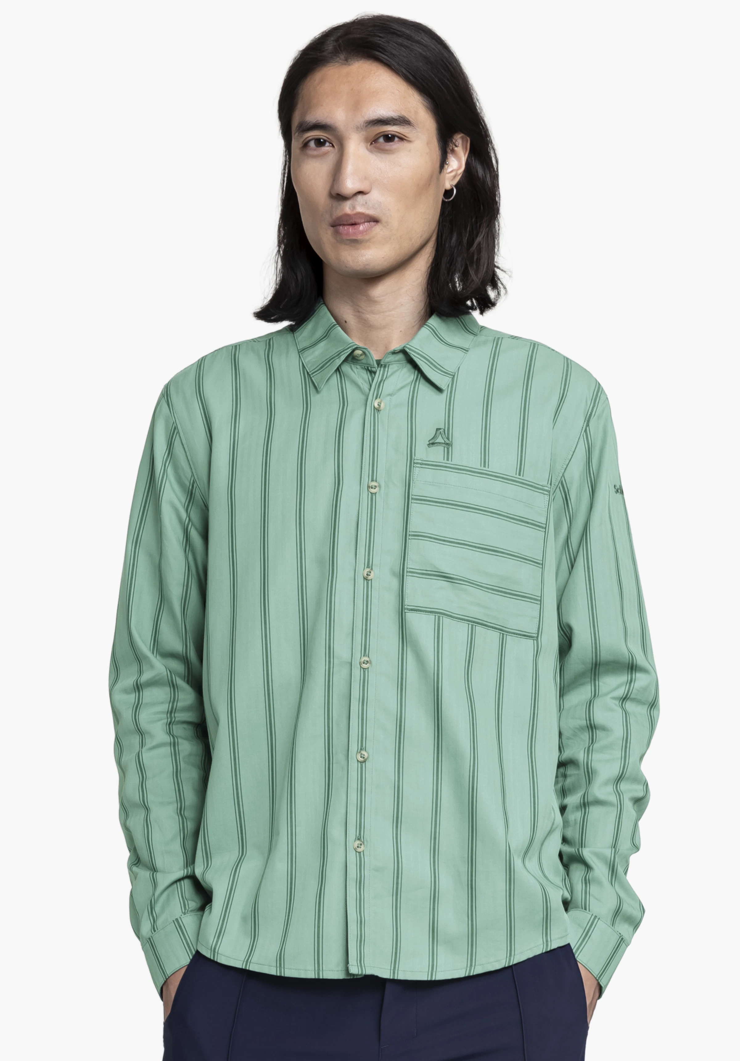 Shirt Style Chanduy MEN in Grün präsentiert von einem Model in Frontalansicht. Er trägt das langärmlige Hemd vor einem neutralen Hintergrund, wobei das dezente Schöffel-Logo auf der Brusttasche gut erkennbar ist.