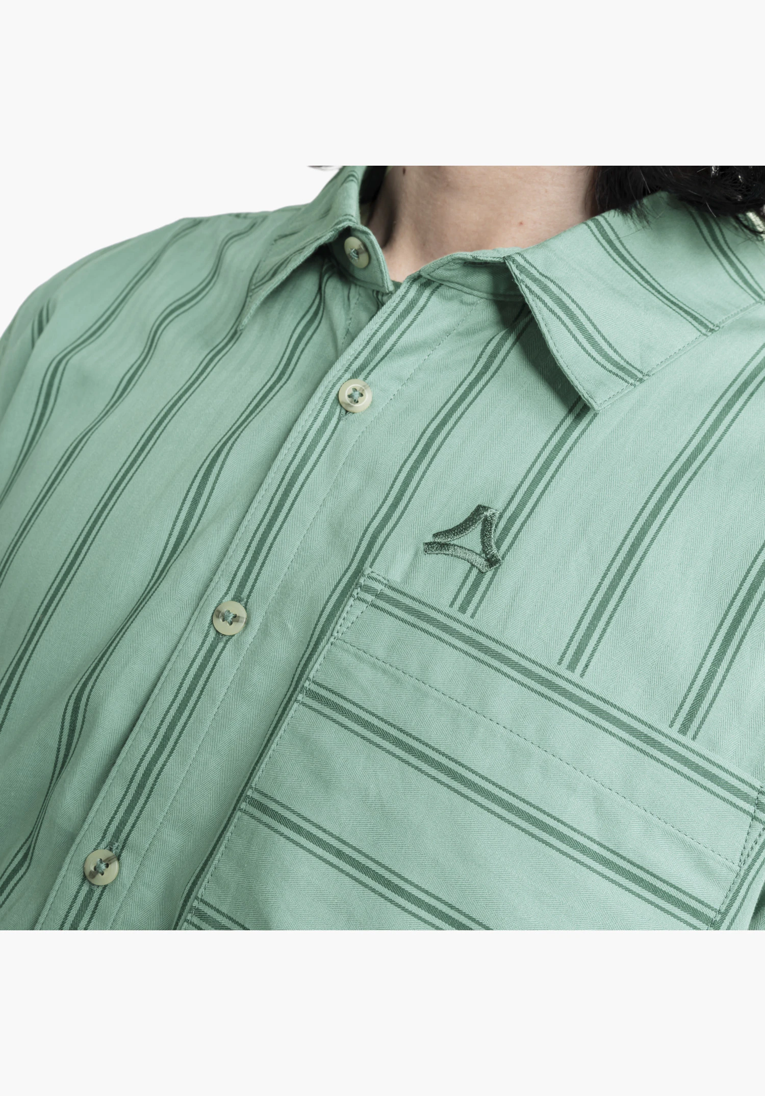 Shirt Style Chanduy MEN montre le logo Schöffel brodé au-dessus de la poche poitrine, la patte de boutonnage classique et le motif du tissu à rayures en vert dans un gros plan sur fond blanc/neutre.