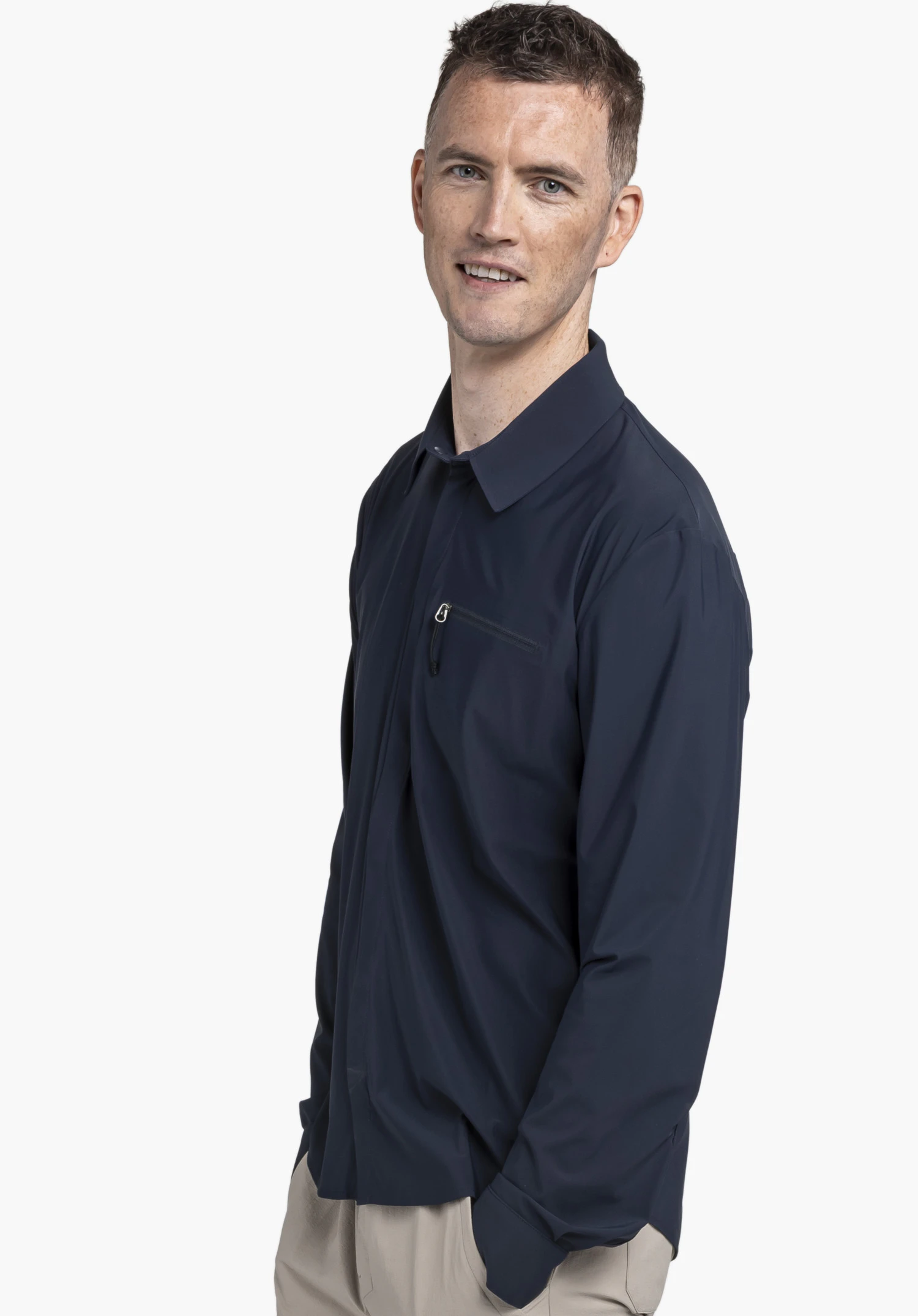 Jersey Shirt Style Calmay MEN en bleu, présentant un mannequin de profil sur un fond neutre. Il porte la chemise à manches longues, mettant en valeur la poche poitrine zippée et le col classique. Le logo Schöffel discret sur le haut du bras complète le look fonctionnel.