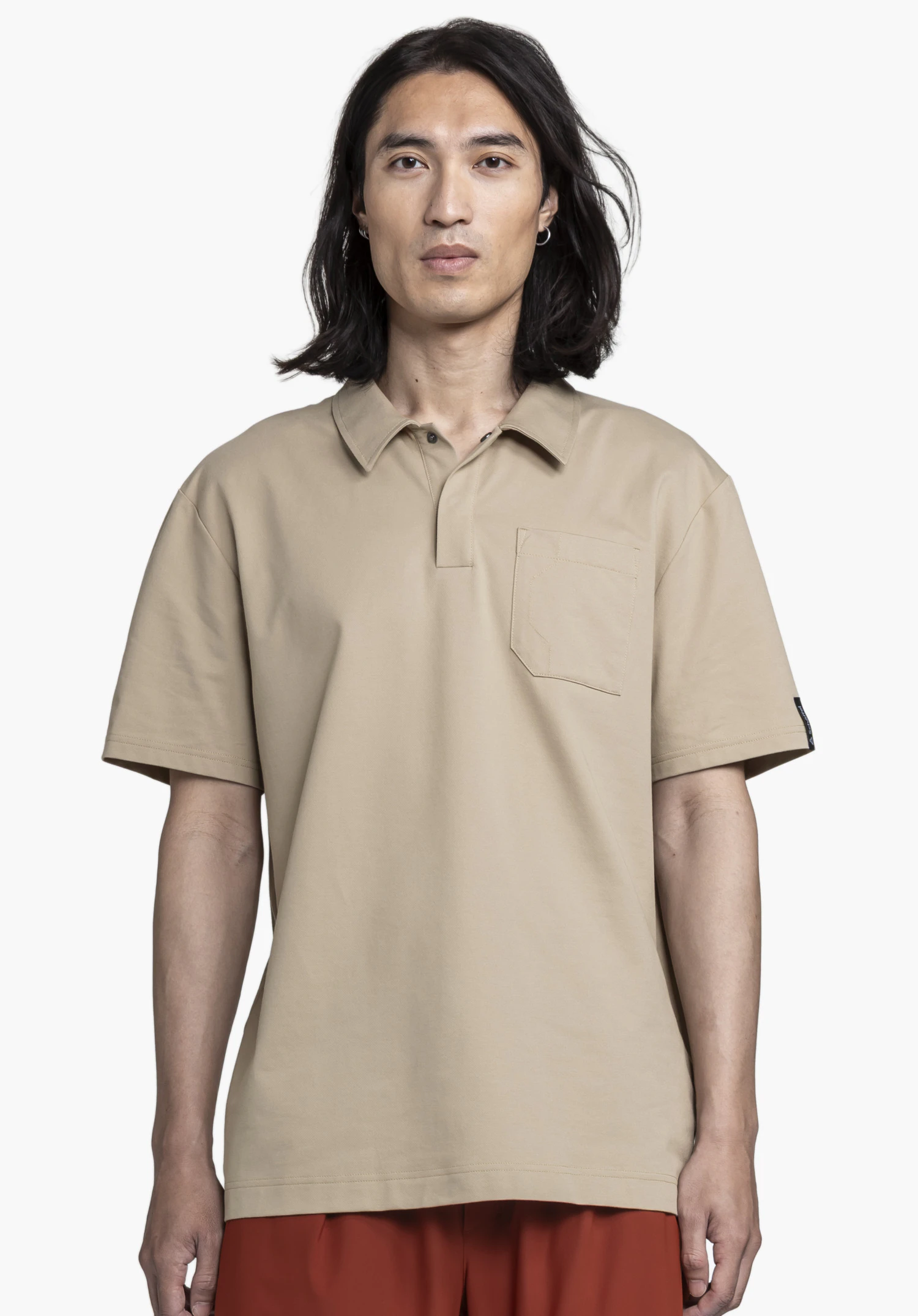 Polo Shirt Style Serenio MEN präsentiert sich in einem eleganten Beige vor neutralem Hintergrund. Ein männliches Model steht frontal zur Kamera und trägt das Polo, wobei das dezente Schöffel-Logo am Ärmel zu sehen ist.