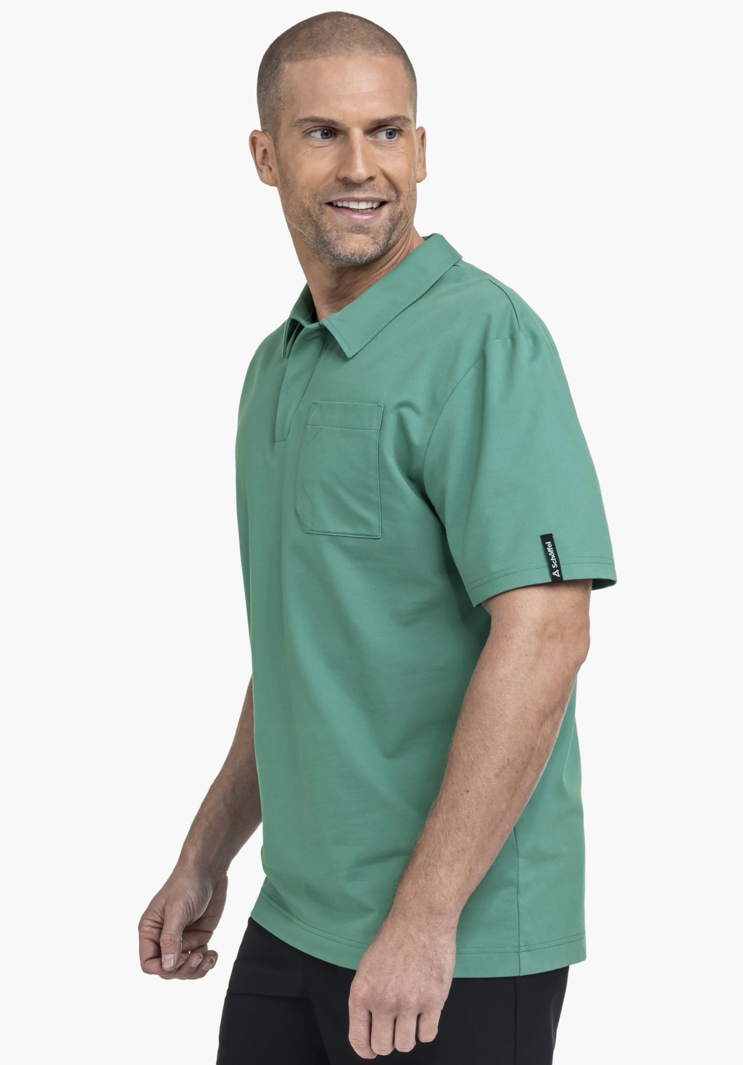 Polo Shirt Style Serenio MEN. Un mannequin se tient de profil et porte le polo vert avec une poche poitrine. Le Schöffel-Logo est visible sur la manche, photographié devant un fond neutre.