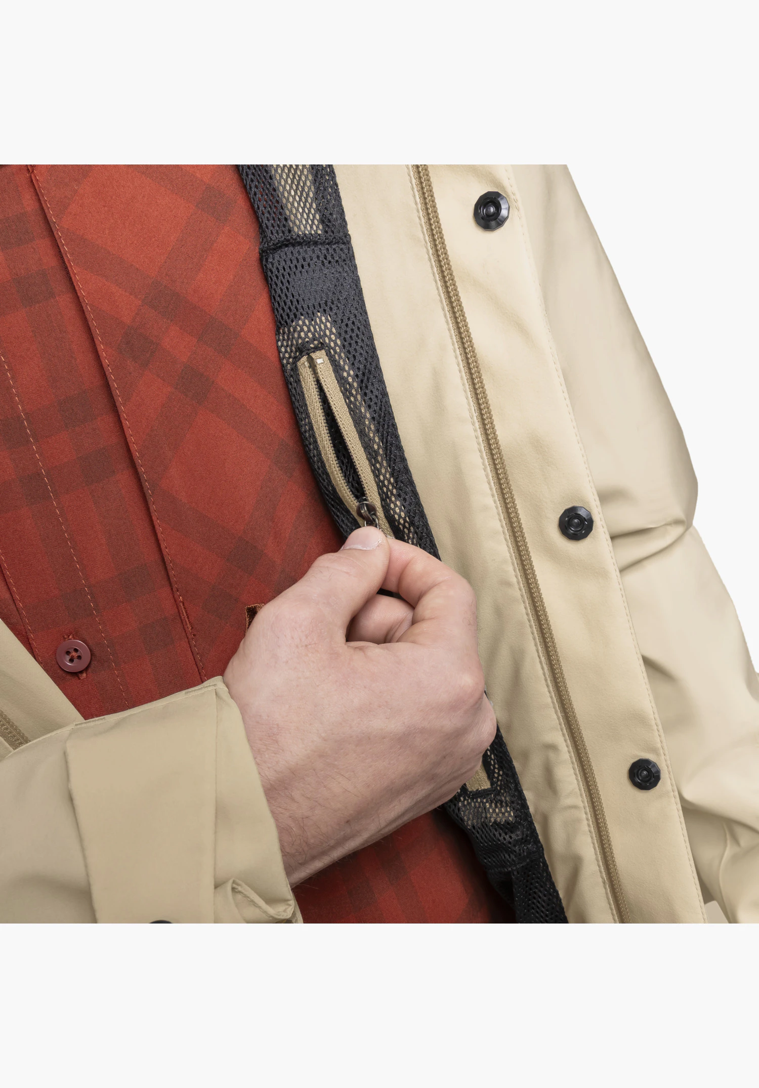 CIRC Jacket Style Smue MEN montre le détail d'une poche intérieure en filet noir avec une fermeture zippée beige actionnée par une main, à côté de la patte de boutonnage avant beige avec des boutons-pression noirs. Gros plan sur fond blanc/neutre.