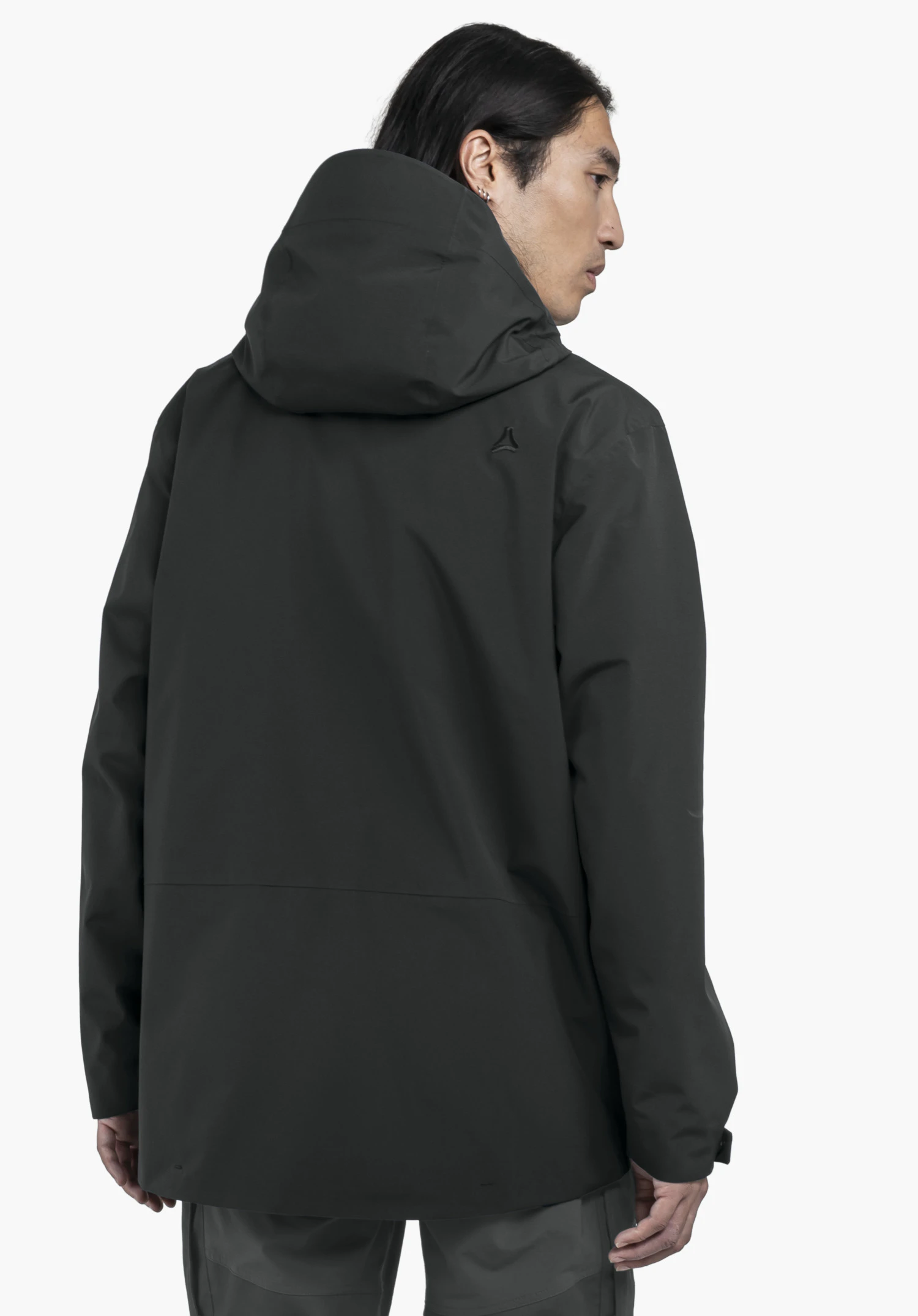 CIRC Jacket Style Smue MEN worn by a model in a back view. The black jacket features a hood and shows the Schöffel logo on the right shoulder area. The model stands slightly turned against a neutral background.