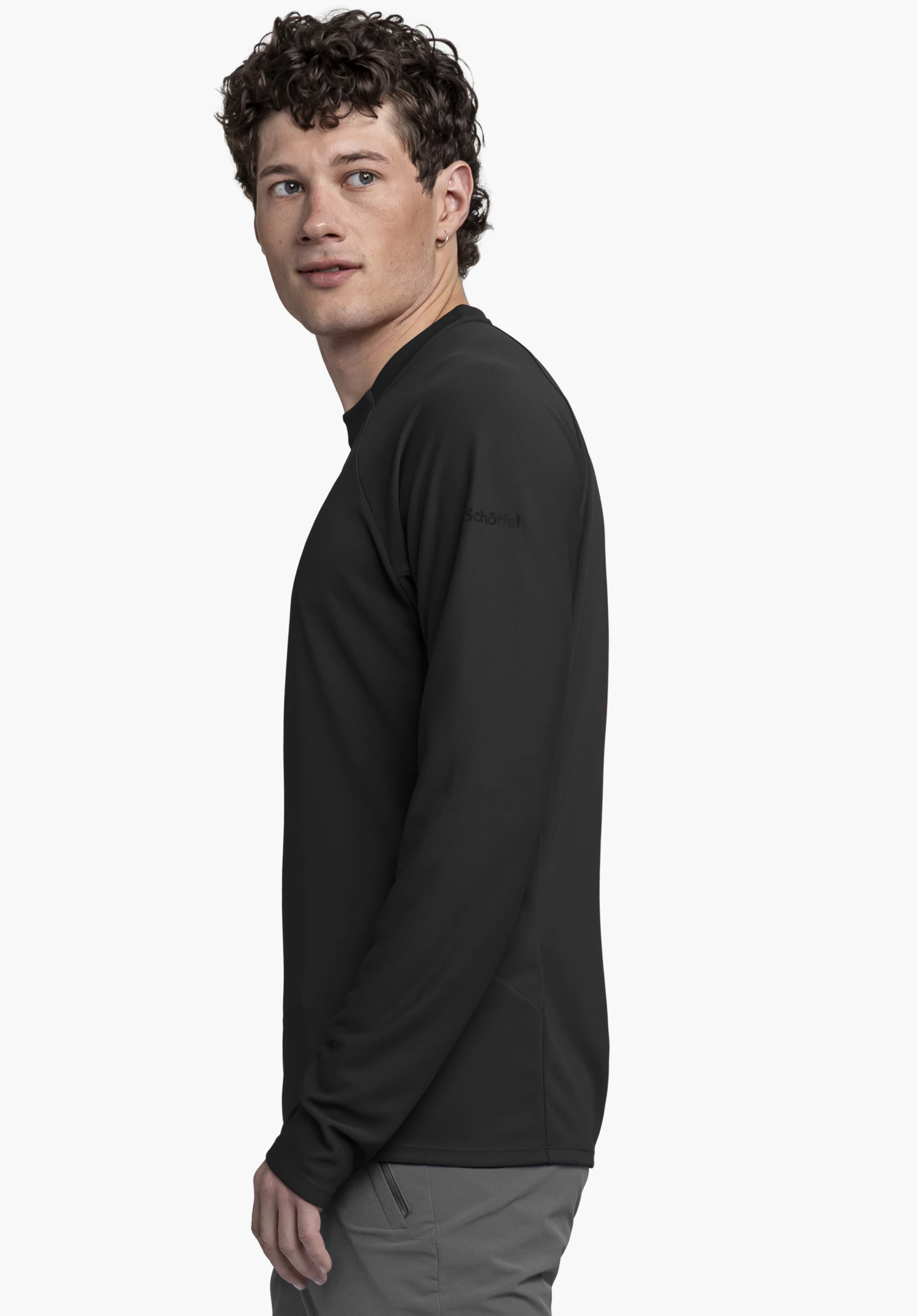 Longsleeve Style Enixa MEN in black: The model is positioned in a side view against a neutral background, showcasing the long-sleeved shirt with the subtle, tonal Schöffel logo visible on the upper arm.