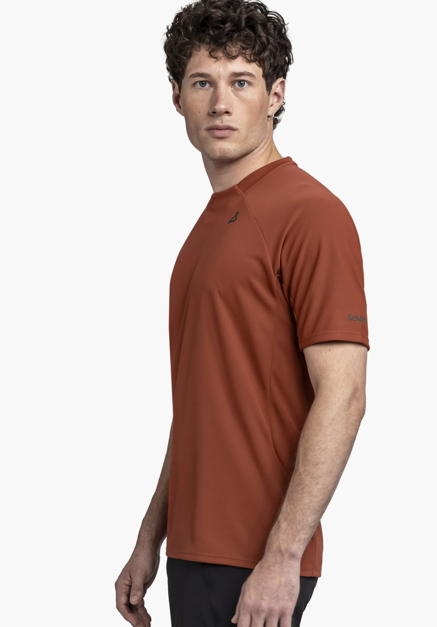 T Shirt Style Enixa MEN: A model wearing the T-shirt in red stands sideways against a neutral background while looking directly at the camera. The subtle Schöffel logo is clearly visible on the sleeve.