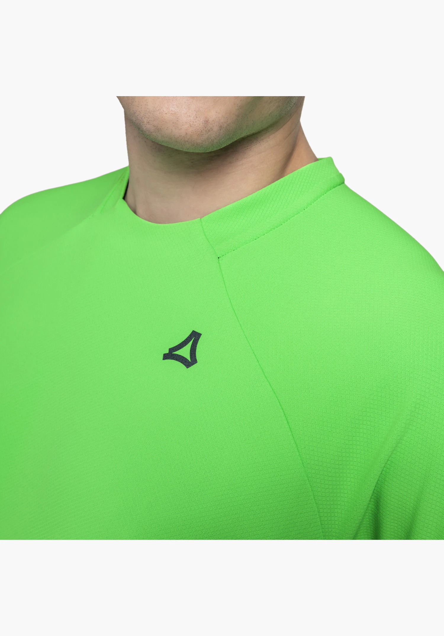 T Shirt Style Enixa MEN zeigt das dezente schwarze Schöffel-Logo auf der Brust und die feine Textur des grünen Funktionsmaterials im Bereich des Kragens. Nahaufnahme vor weißem/neutralem Hintergrund.