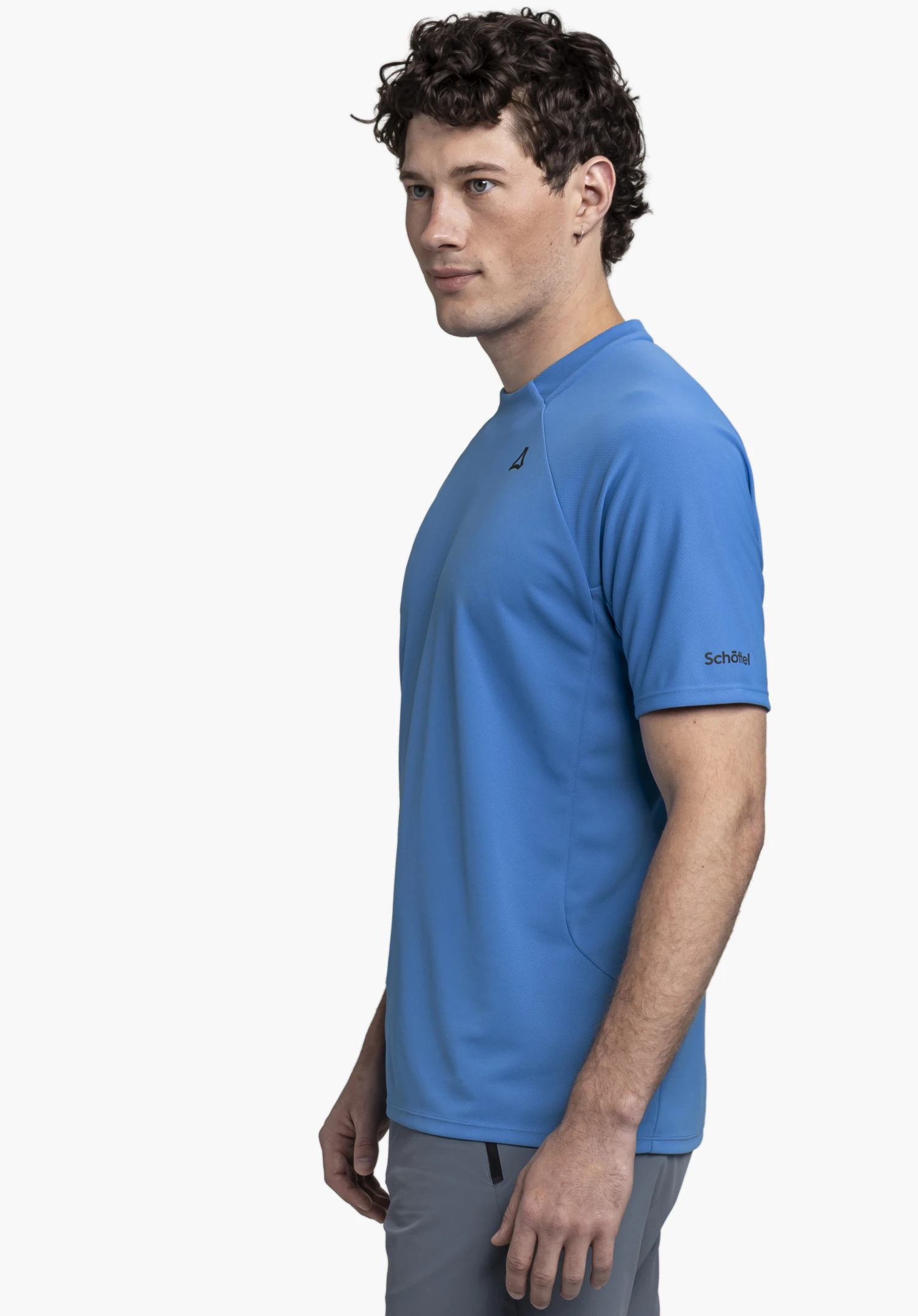 T Shirt Style Enixa MEN: The model stands sideways against a neutral background, showcasing the shirt in a vibrant blue. The subtle Schöffel logo is clearly visible on the sleeve.