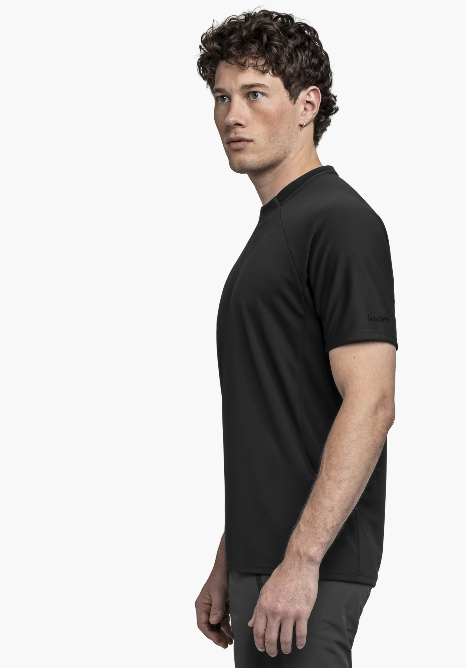 T Shirt Style Enixa MEN: A model wearing a black t-shirt is standing sideways against a neutral background. The focus is on the fit, with the subtle Schöffel logo clearly visible on the sleeve.