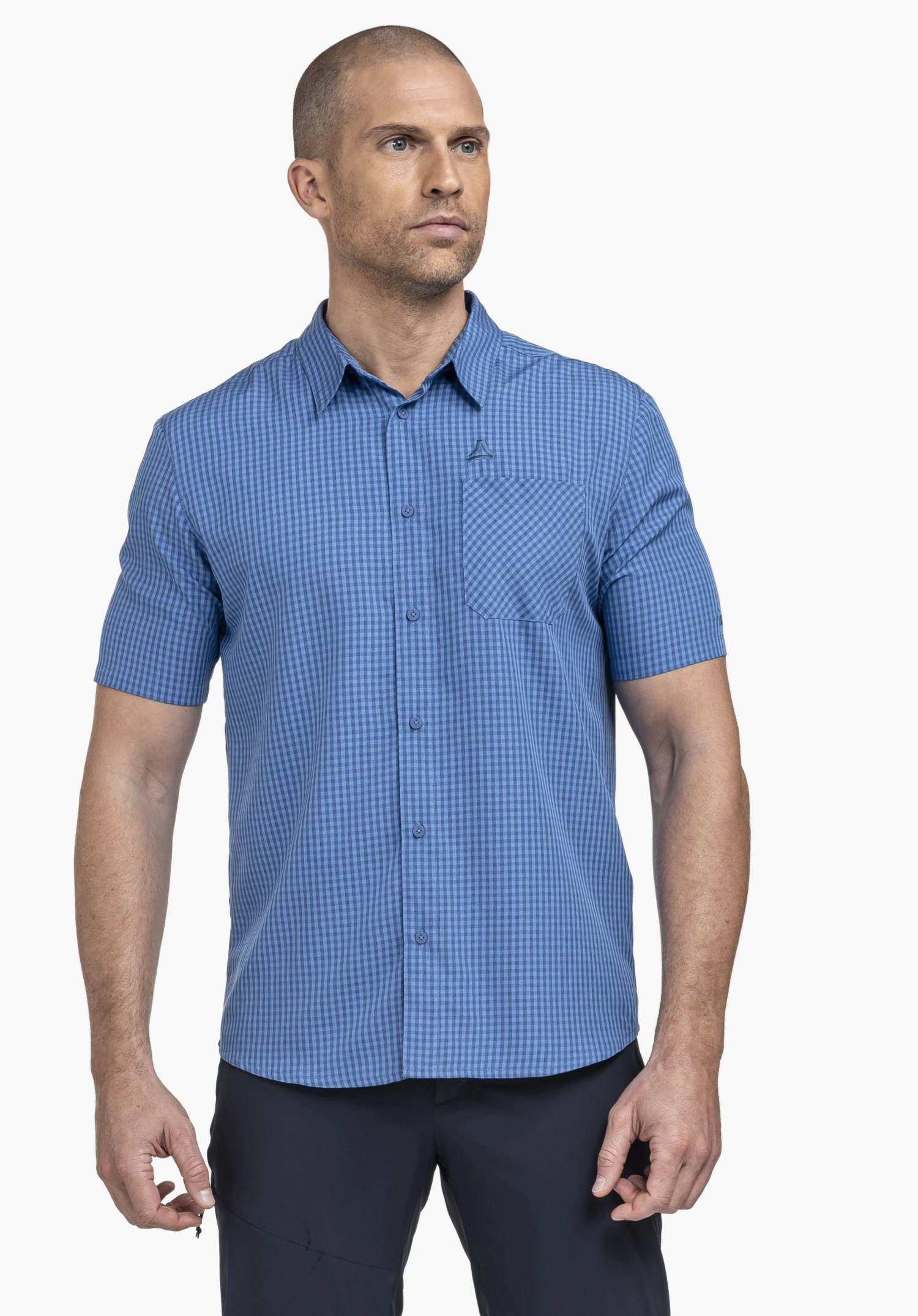 CIRC Shirt Style Dalfoss MEN: Das Modell steht frontal vor einem neutralen Hintergrund und trägt das kurzärmelige Hemd in Blau mit klassischem Karomuster. Auf der Brusttasche ist das dezente Schöffel-Logo sichtbar, das den funktionalen Look unterstreicht.