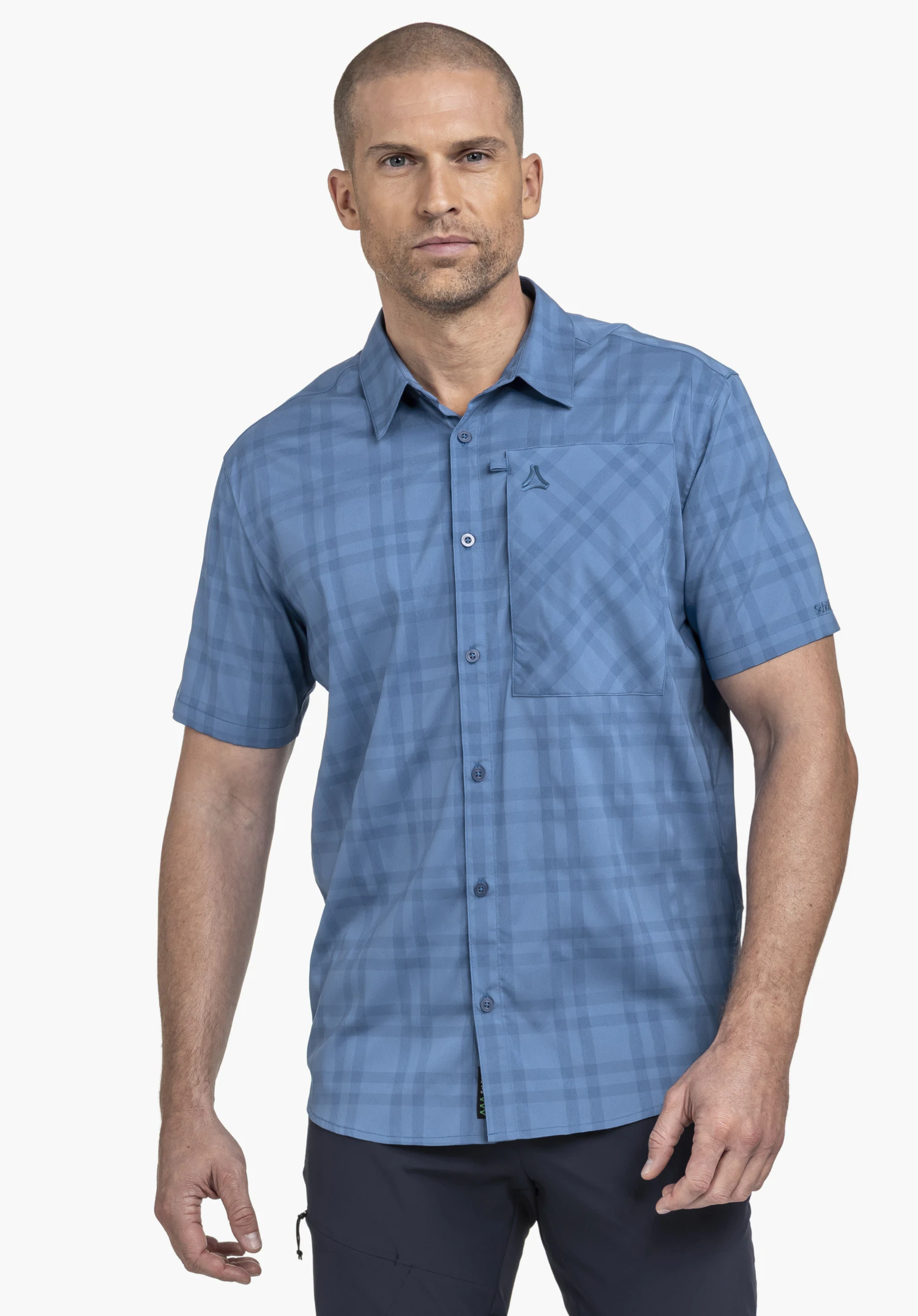Shirt Style Frolya MEN in Blau: Das Model steht frontal vor einem neutralen Hintergrund und trägt das kurzärmelige Hemd mit dezentem Karomuster. Das kleine Schöffel-Logo ist dezent auf der Brusttasche platziert.