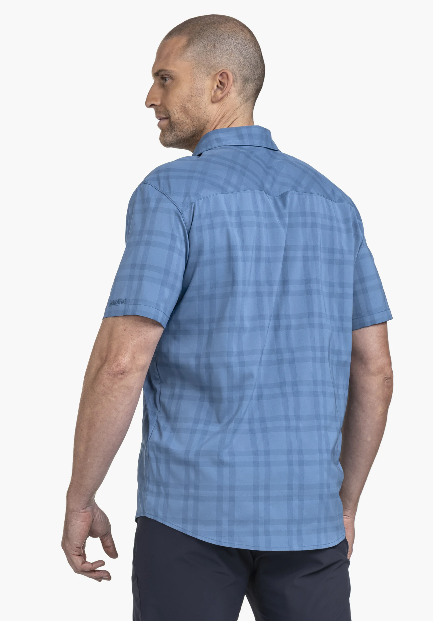 Shirt Style Frolya MEN in blue: The model is captured in a slight back view, highlighting the casual fit of the shirt. The subtle Schöffel logo is visible on the sleeve, set against a neutral background.