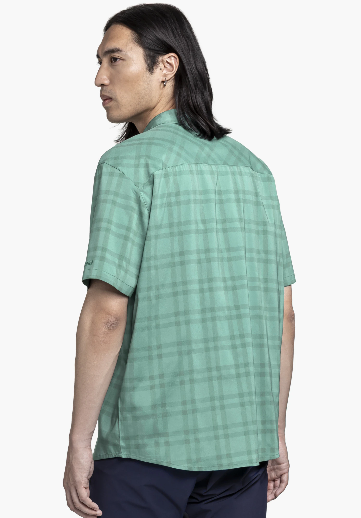 Shirt Style Frolya MEN in green: The model is seen from the back with their head turned slightly, set against a neutral background. The checked shirt offers a casual look, complemented by the subtly embroidered Schöffel logo on the sleeve for a premium touch.