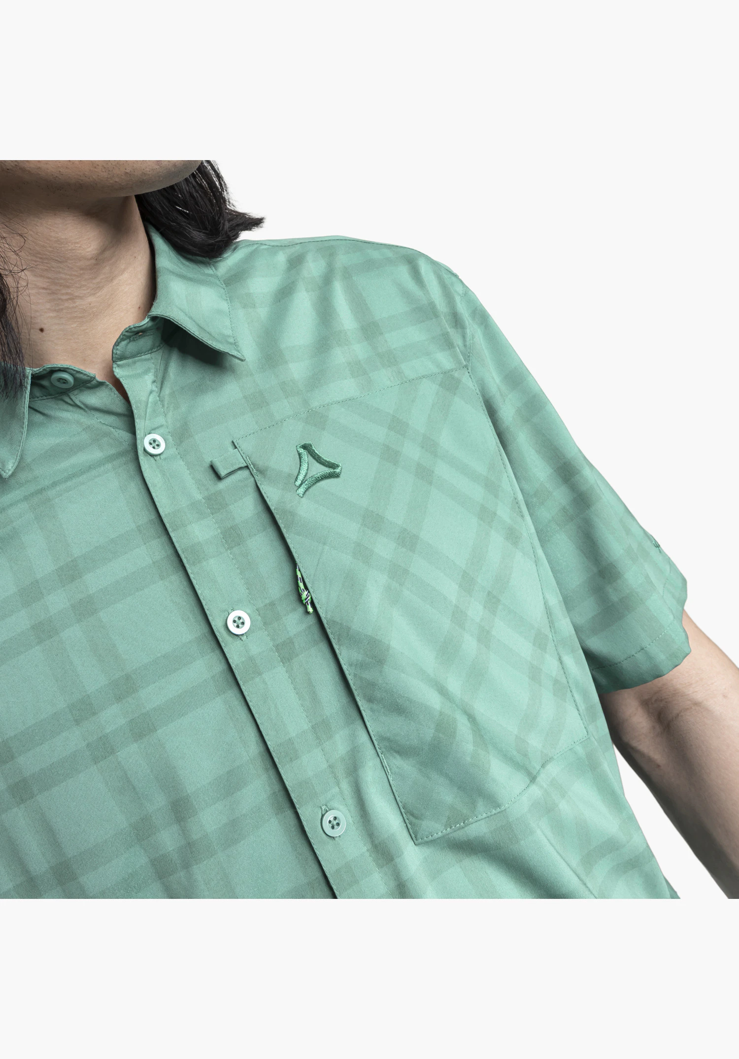 Shirt Style Frolya MEN, detail view of the chest pocket. Visible are the vertical zip with a small pull cord, the front button placket, the subtle check pattern on the green fabric, and the embroidered Schöffel-Logo, close-up against a white/neutral background.