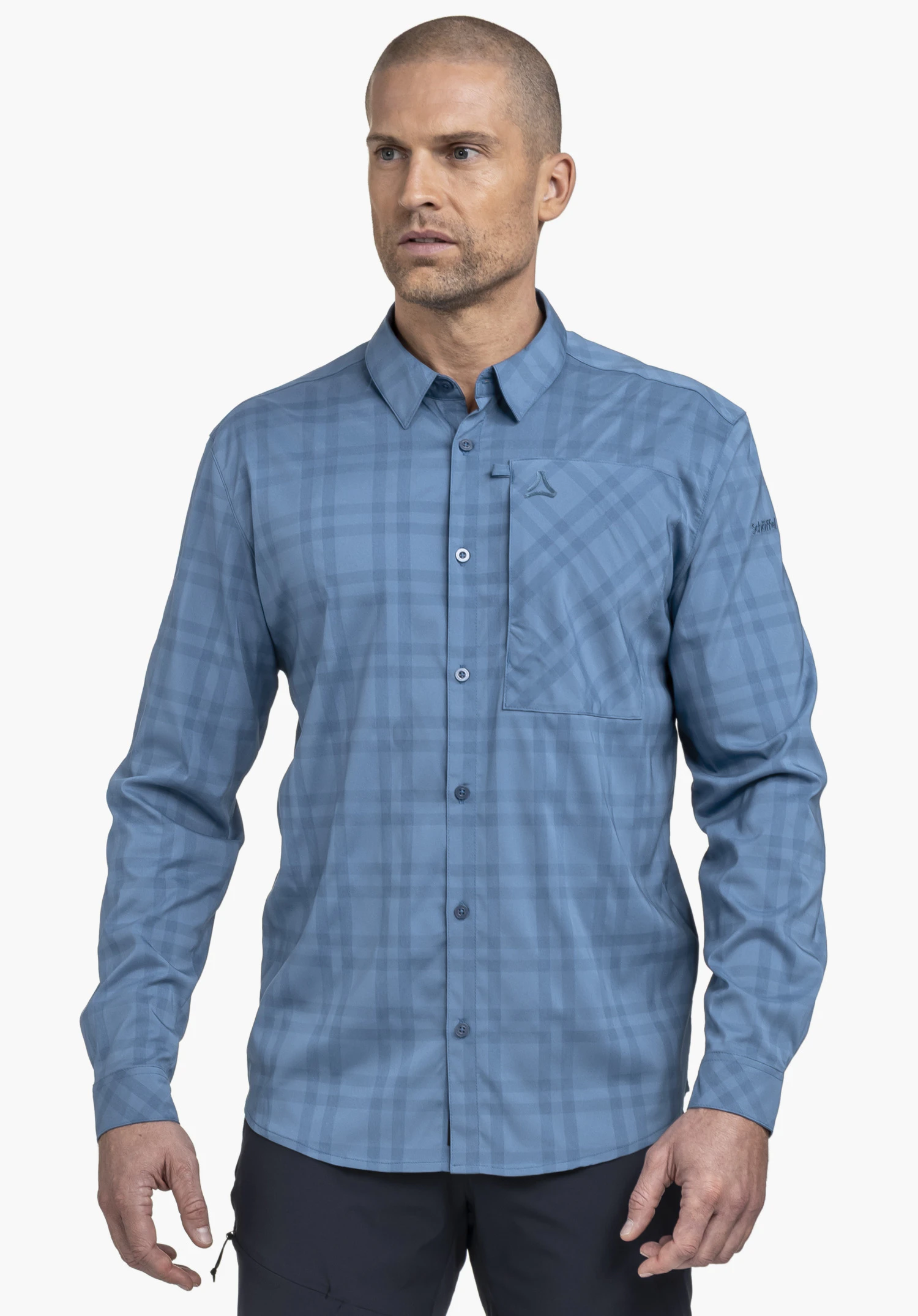 Shirt Style Fraris MEN in Blau. Ein Model steht frontal vor einem neutralen Hintergrund und präsentiert das karierte Hemd mit dezentem Schöffel-Logo auf der Brusttasche und am Ärmel, ideal für stilvolle Outdoor-Abenteuer.