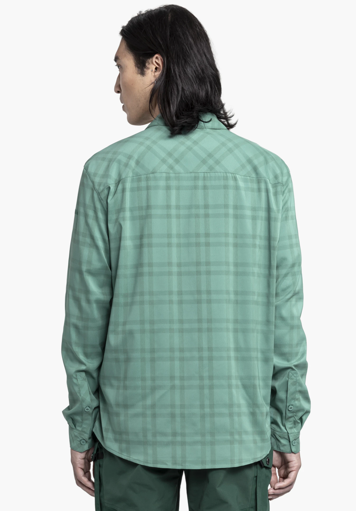 Shirt Style Fraris MEN in Grün. Das Modell ist in einer dezenten Rückenansicht vor einem neutralen Hintergrund zu sehen. Das dezente Schöffel-Logo ist dezent am Ärmel platziert und rundet das Design ab.